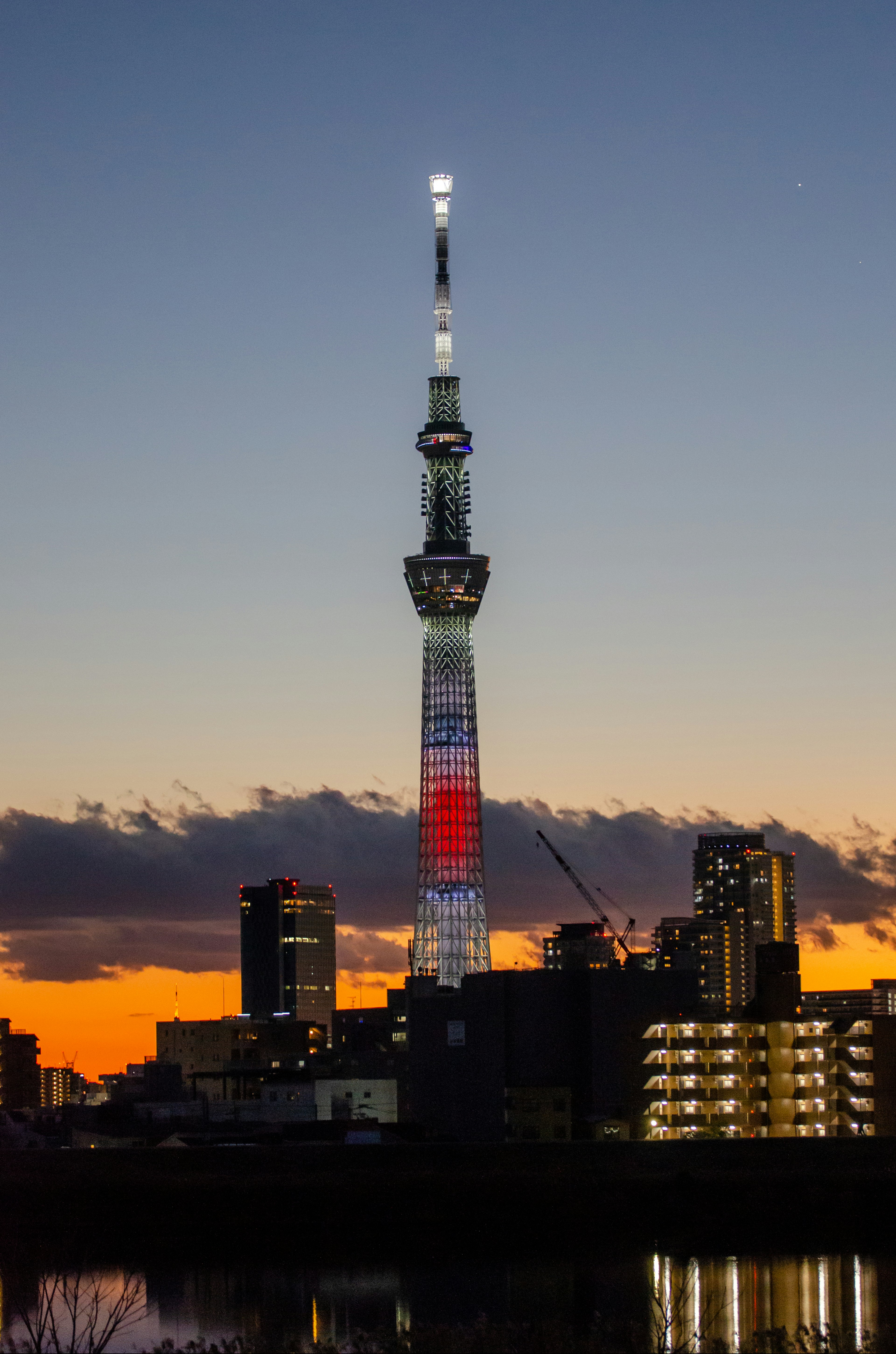 Tokyo Skytree illuminated at dusk with red and white lights