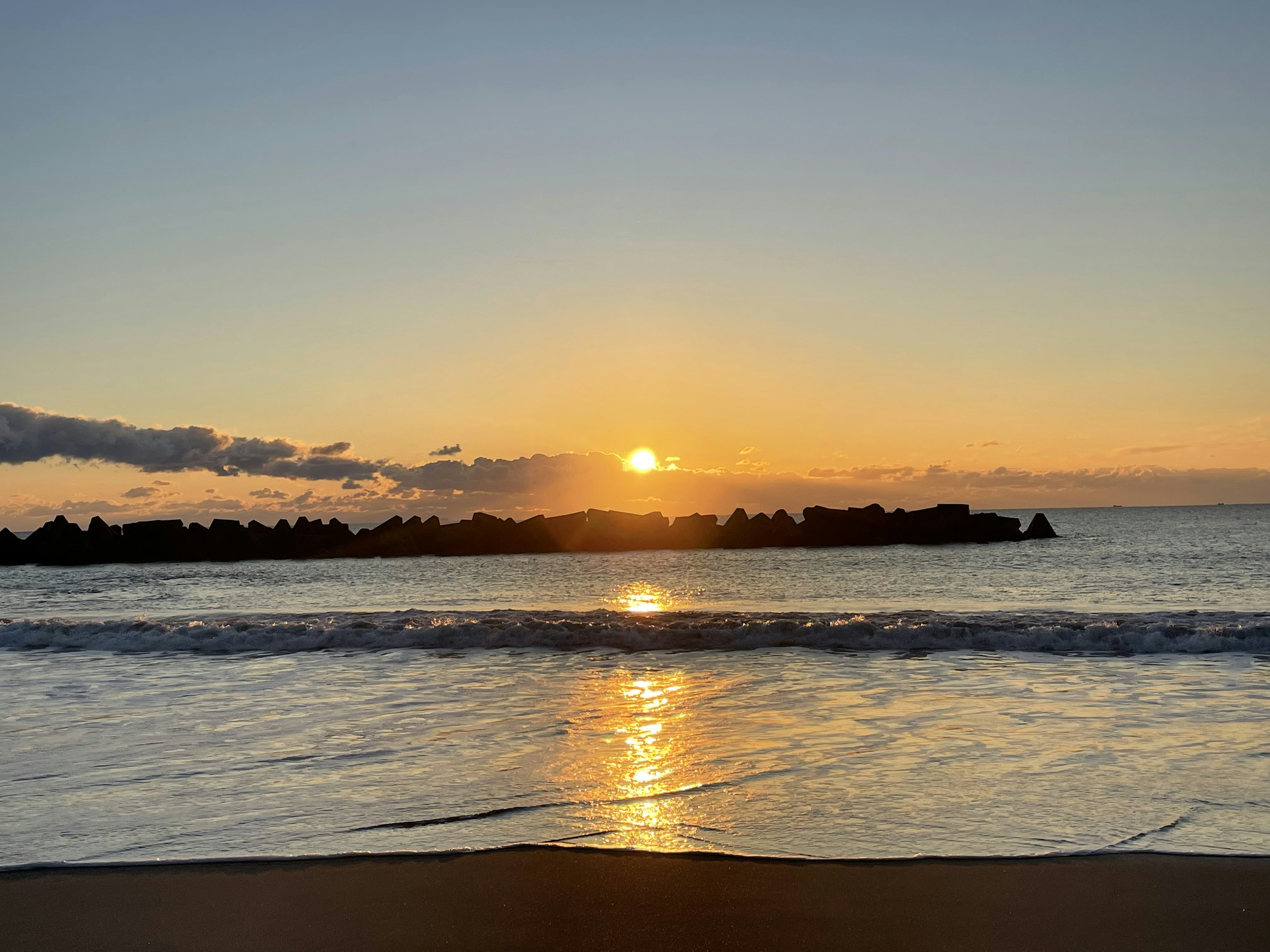 夕日が海に沈む美しい風景 浜辺の波と岩のシルエット