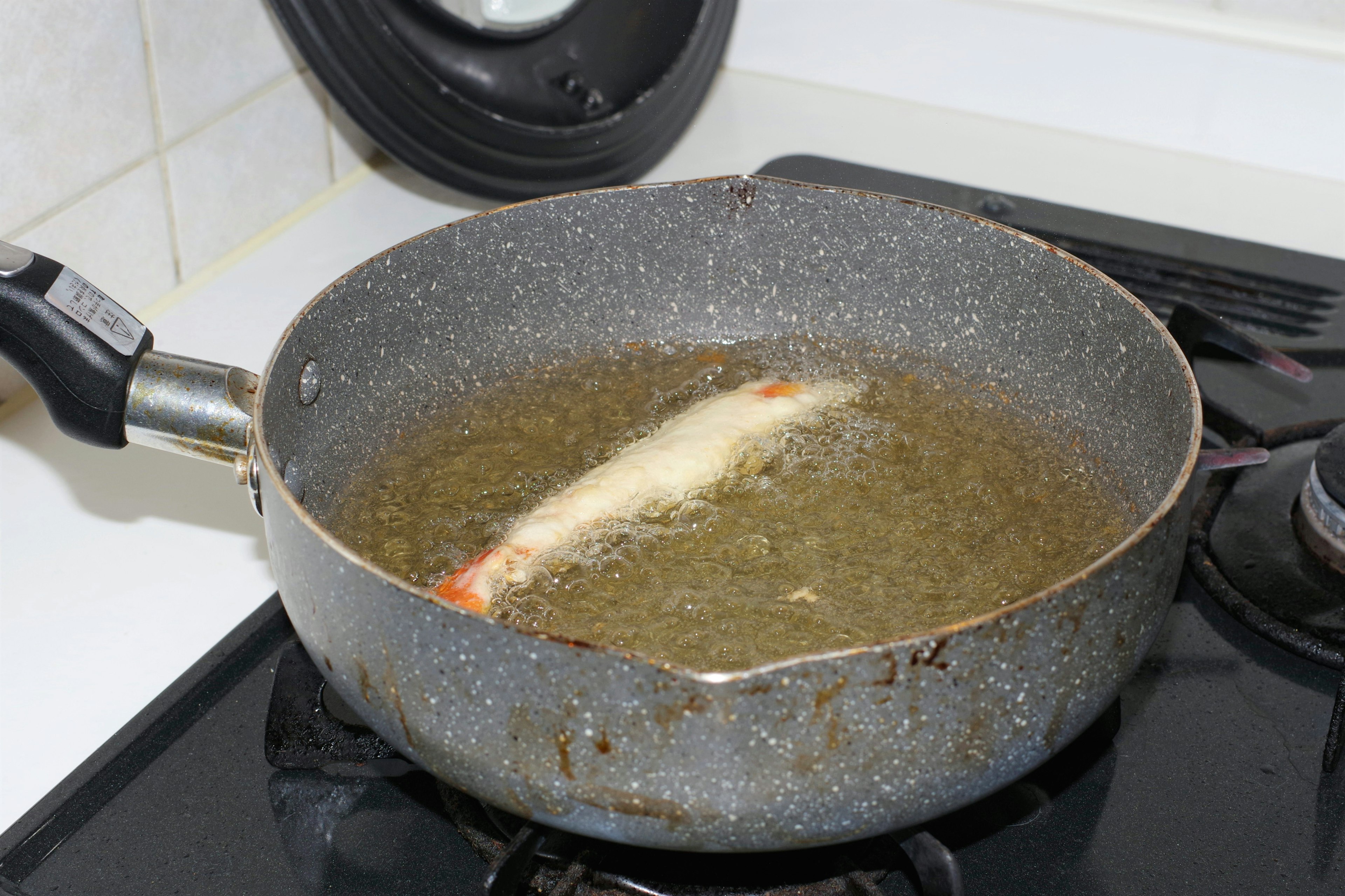 Fillet ikan yang digoreng dalam wajan dengan minyak panas