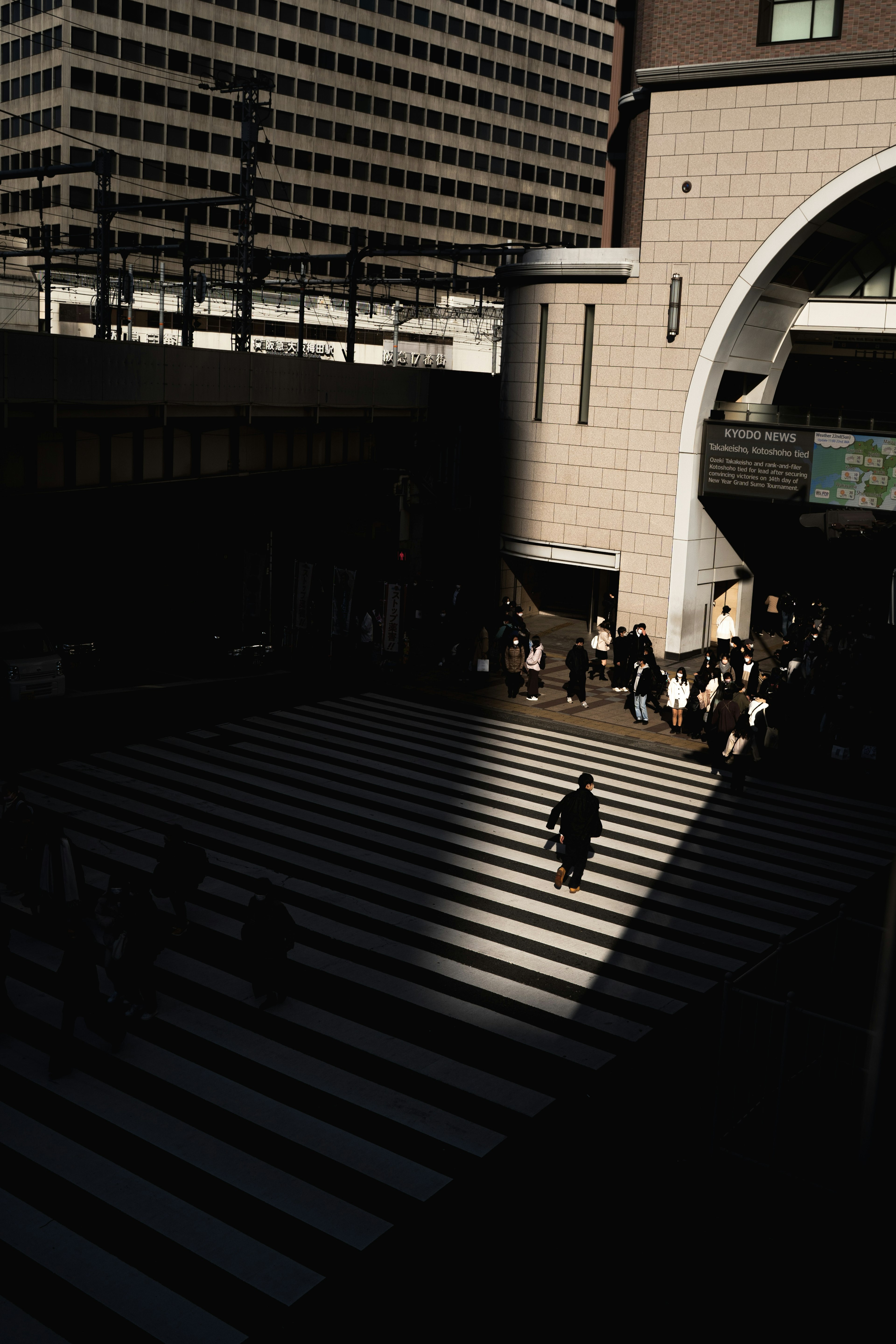 Urban scene with a shadowed crosswalk and visible train station entrance