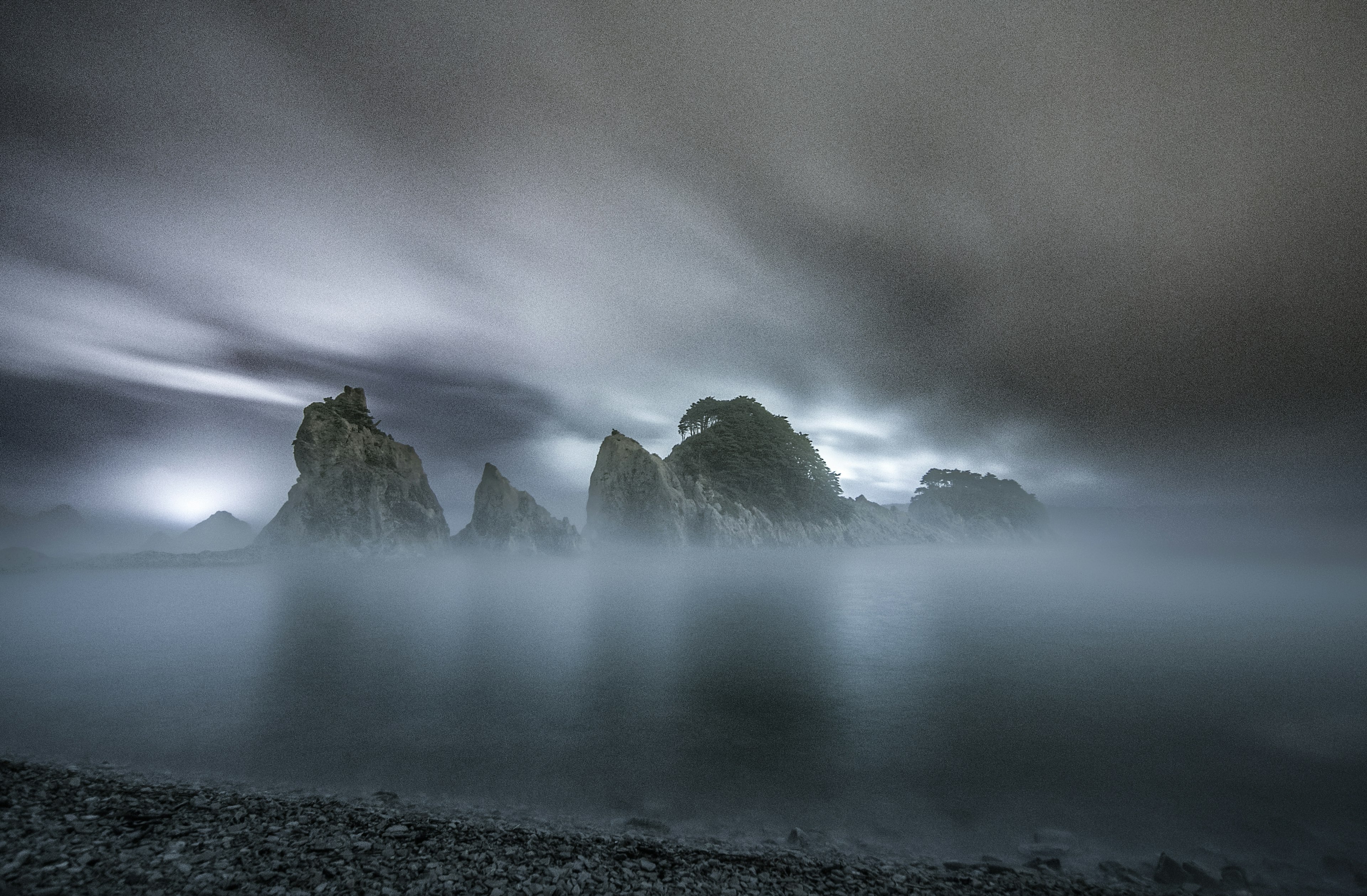 Mysterious fog enveloping jagged rock formations under a dark sky