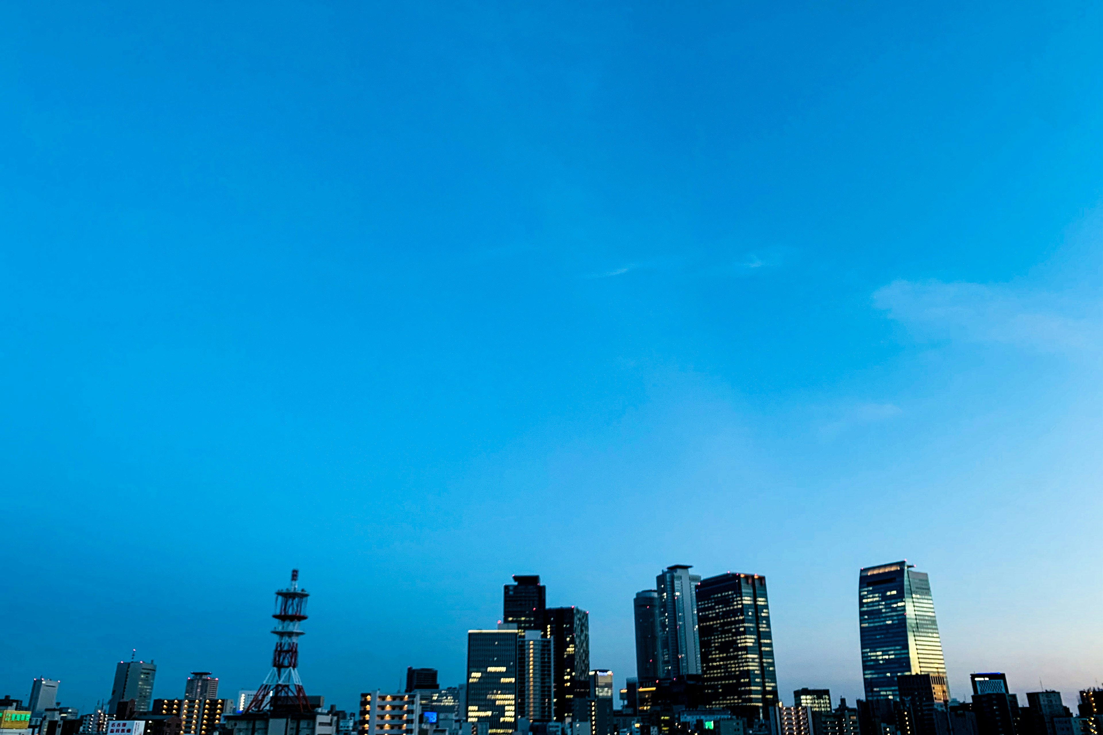 青い空の下に高層ビルが並ぶ都市の景色