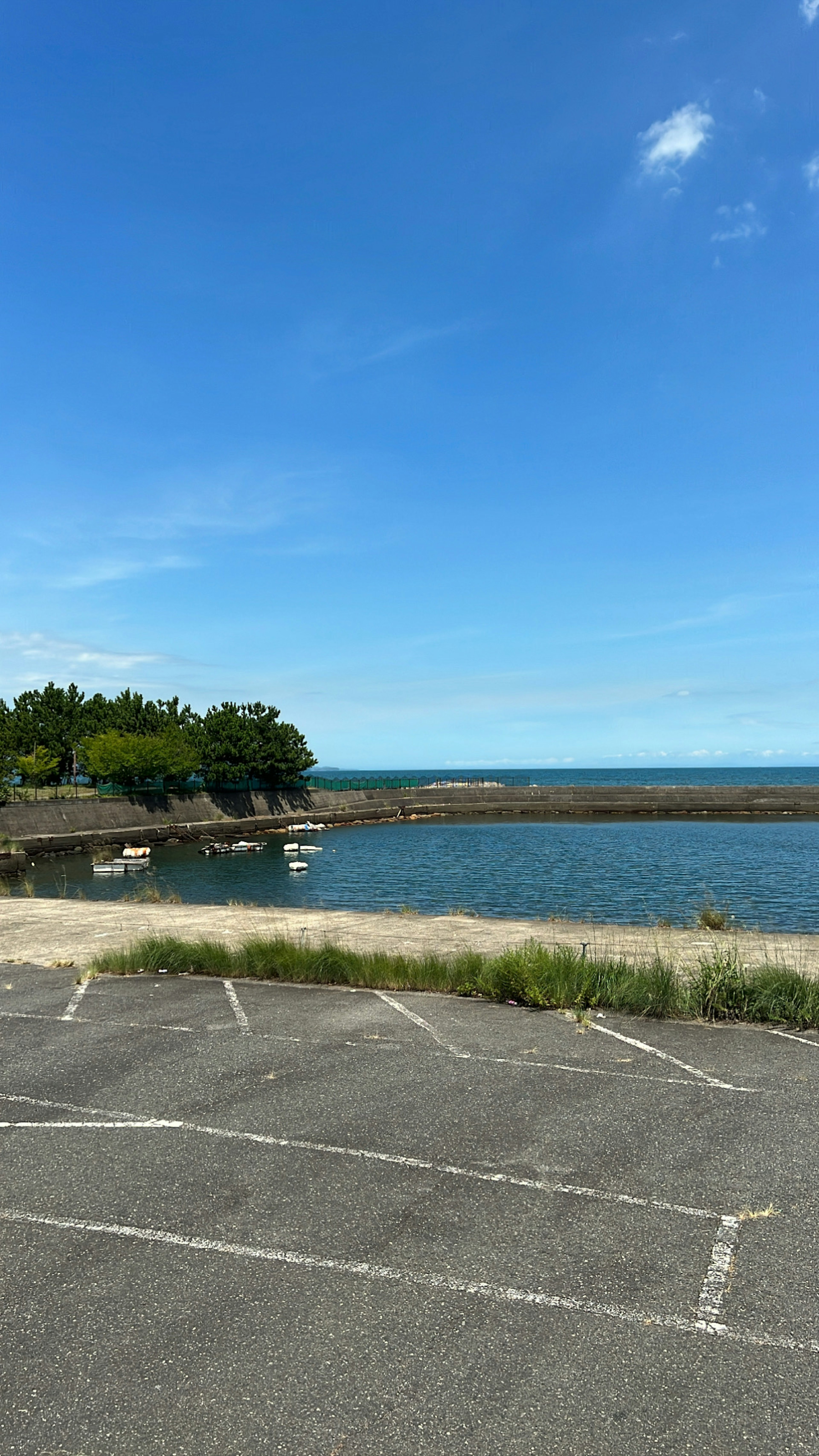 Scenic view of the ocean under a clear blue sky with a parking lot in the foreground