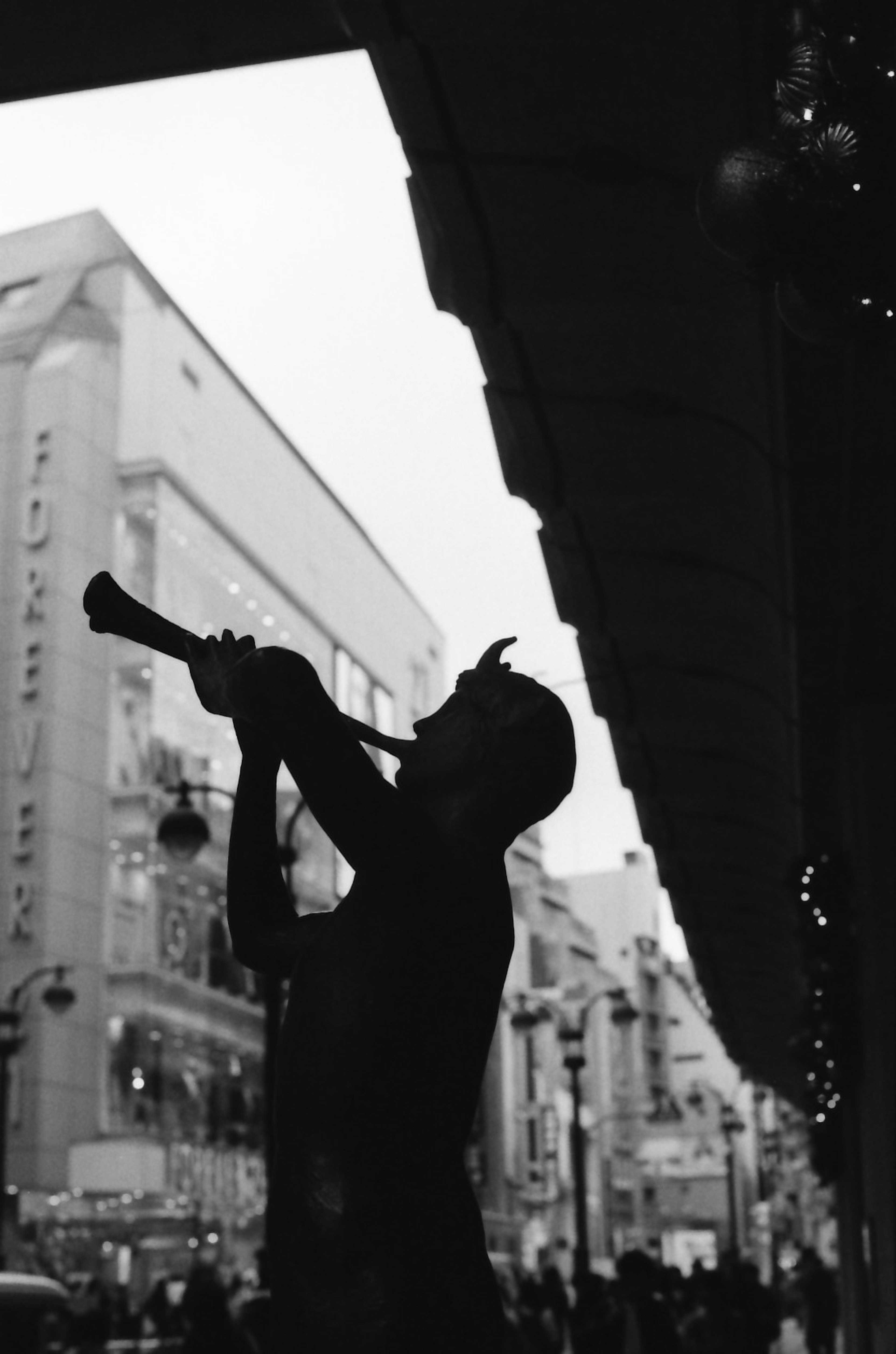 Silhouette di un uomo che suona la tromba all'angolo di una strada con edifici sullo sfondo