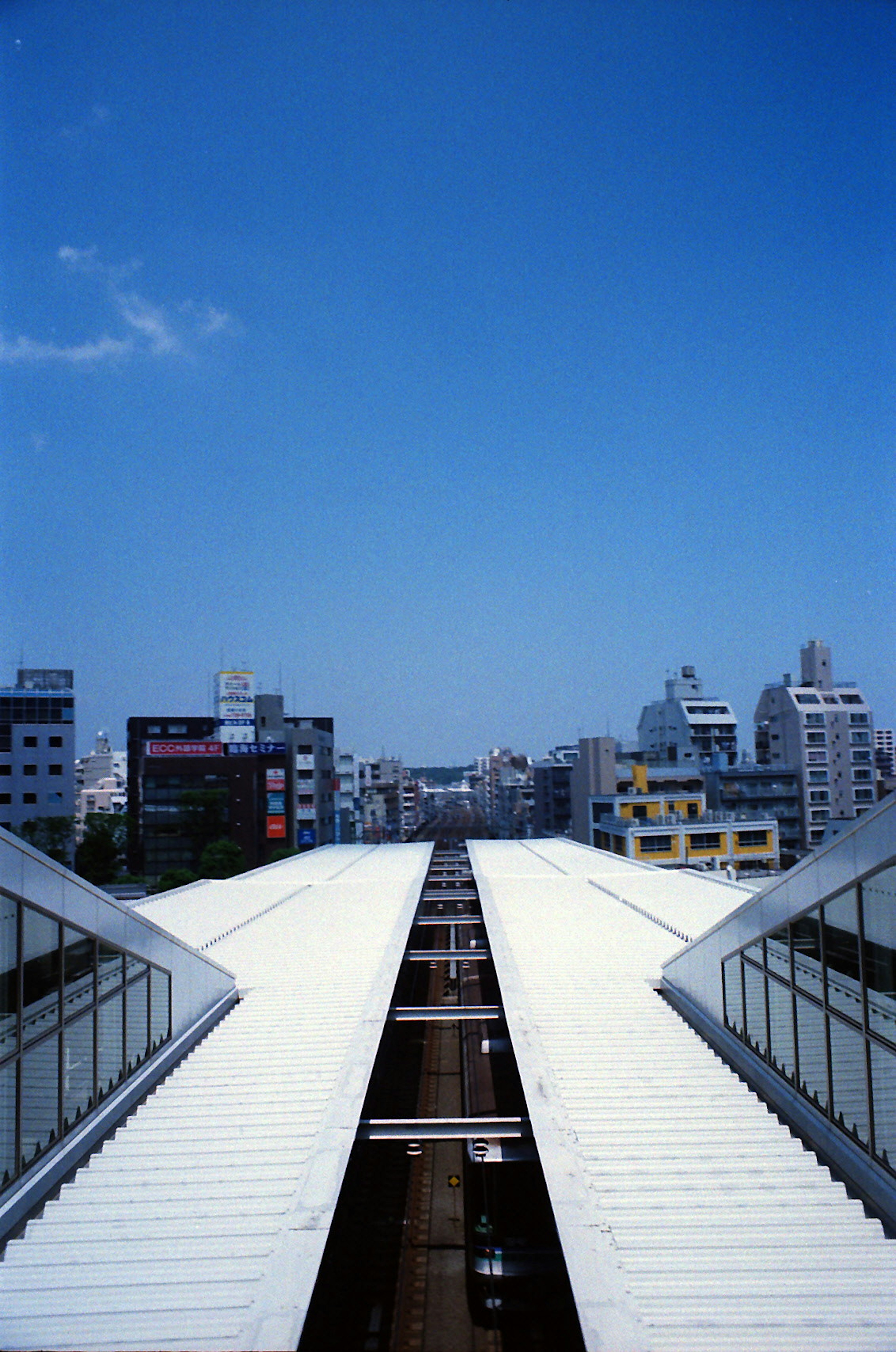 青空の下に広がる都市の景色と白い屋根の線路