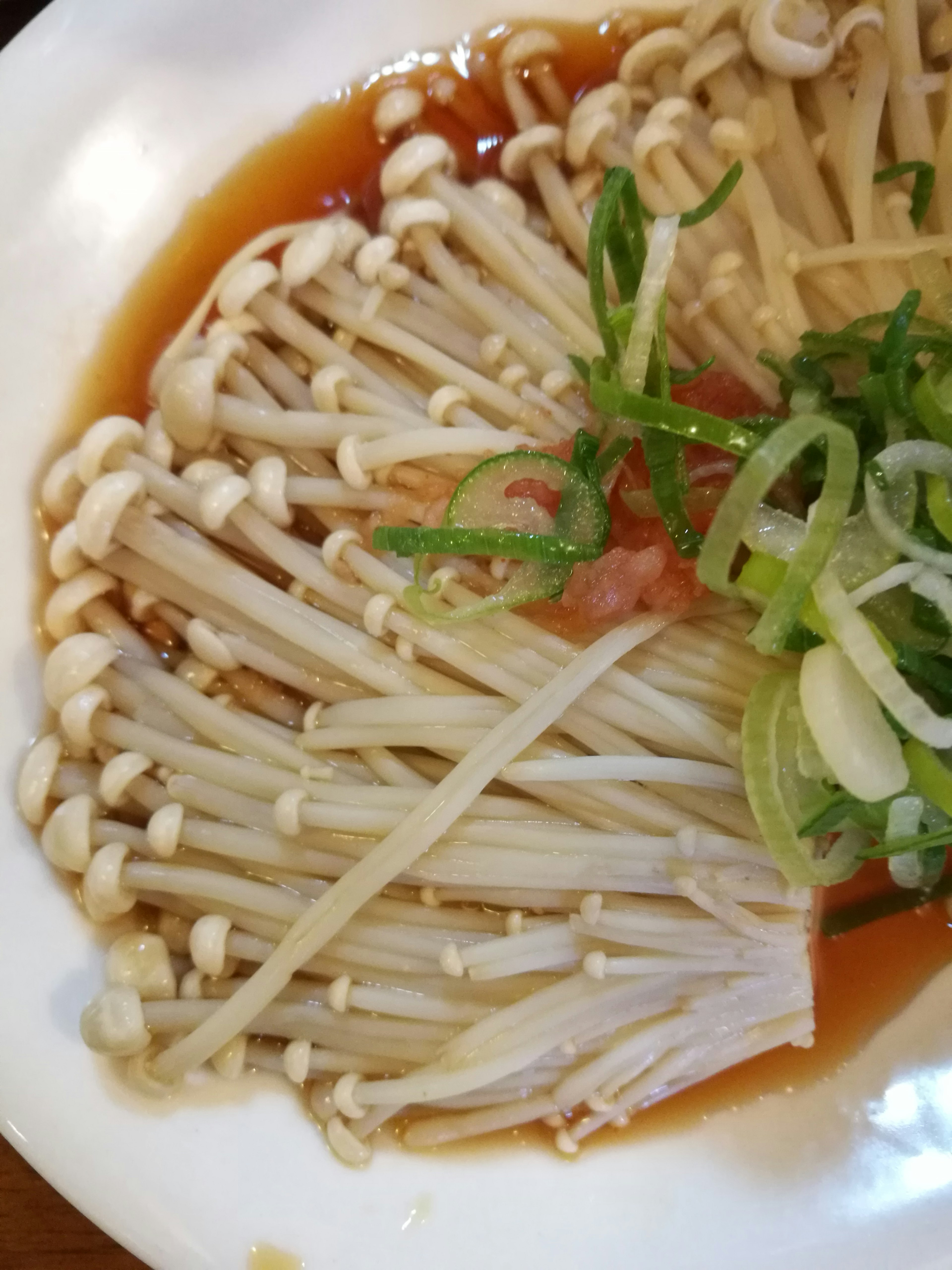 Enoki mushrooms and green onions arranged on a white plate