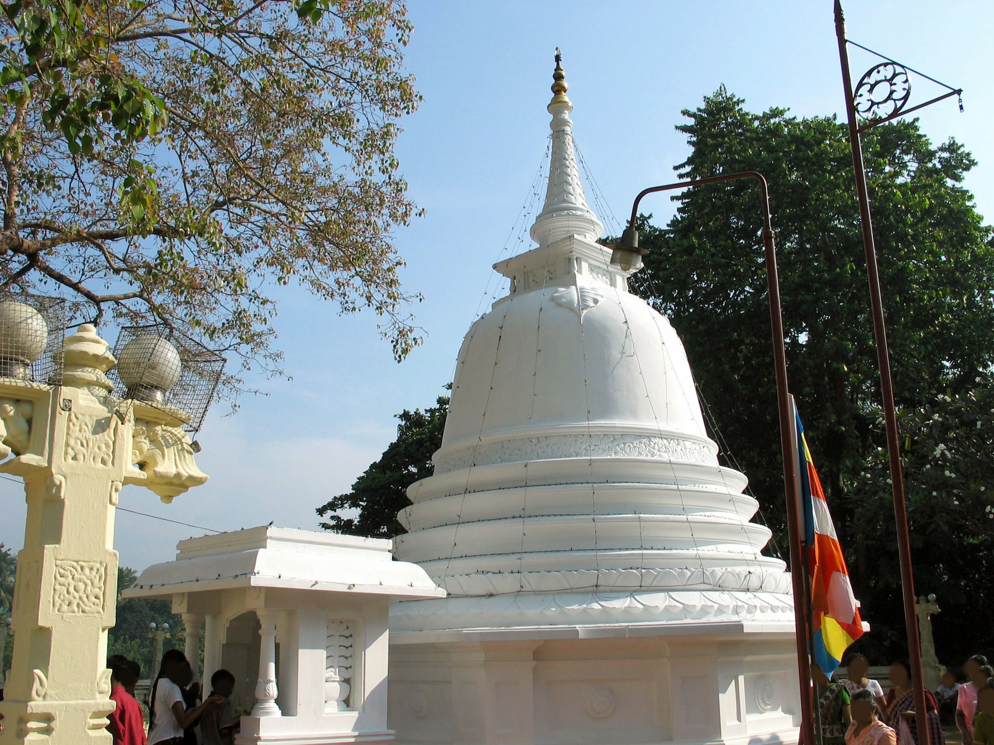 Stupa bianca circondata da una vegetazione lussureggiante e strutture del tempio