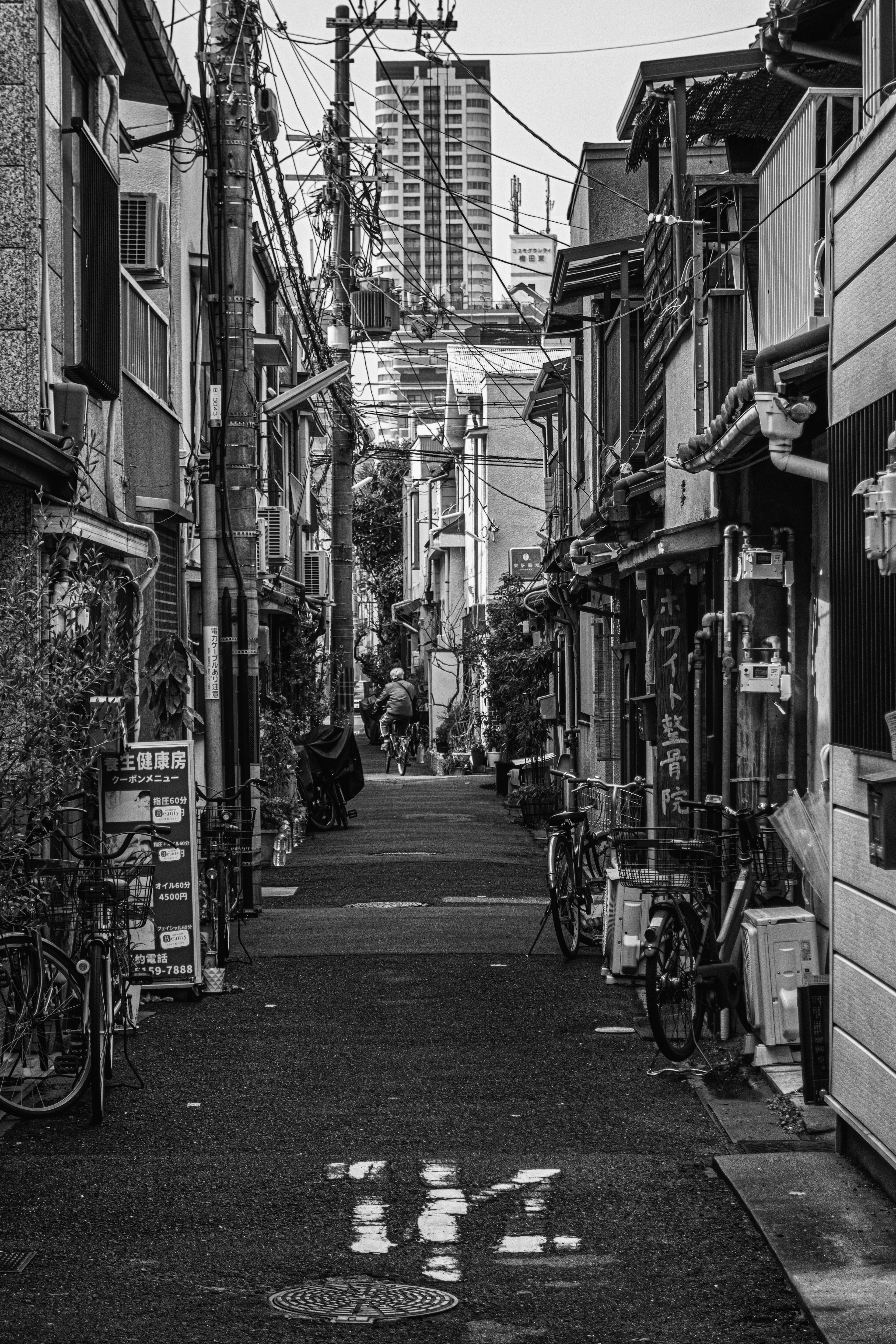 狭い路地に沿って並ぶ建物と自転車が見えるモノクロの風景