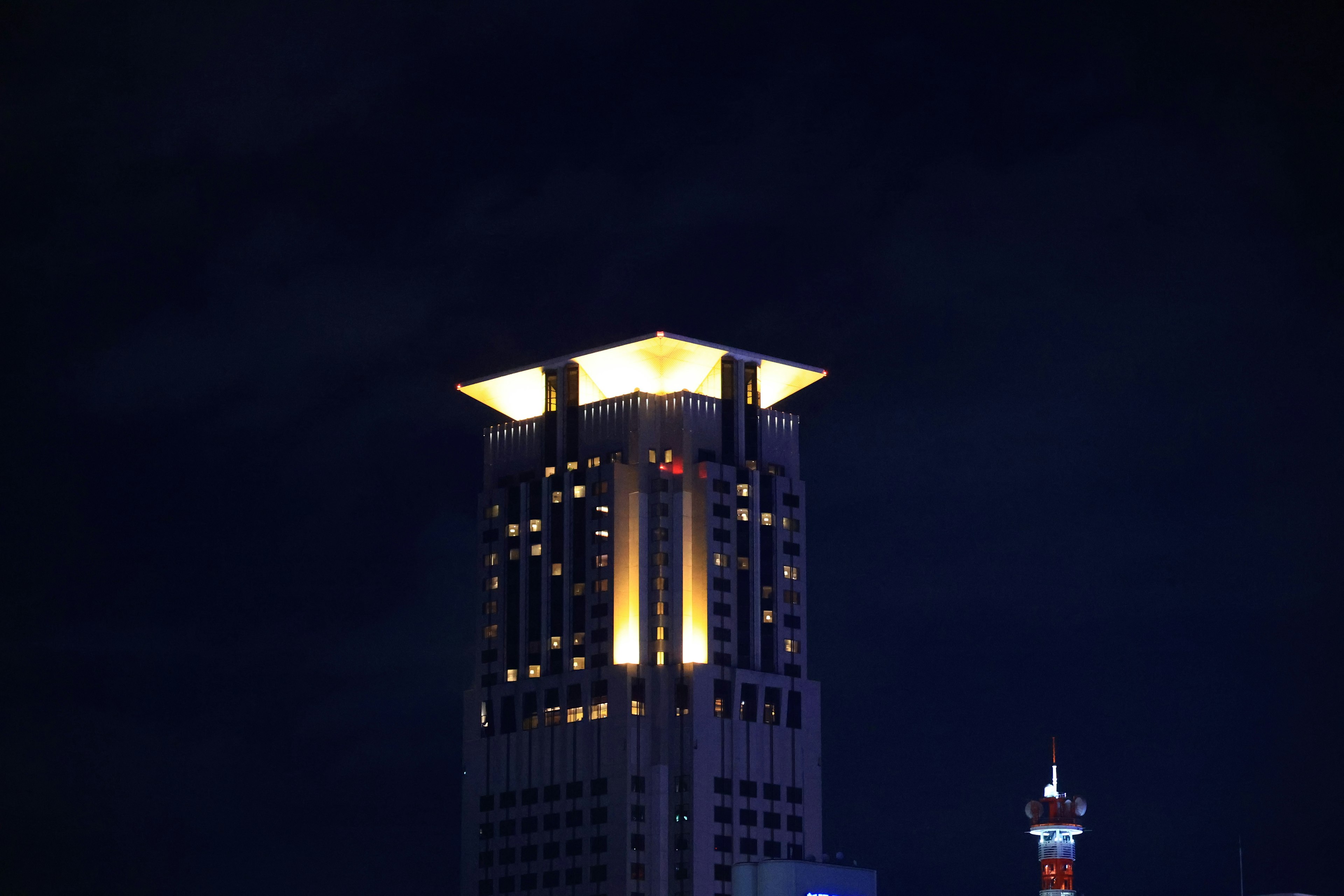 Atap bercahaya dari gedung pencakar langit di latar belakang langit gelap