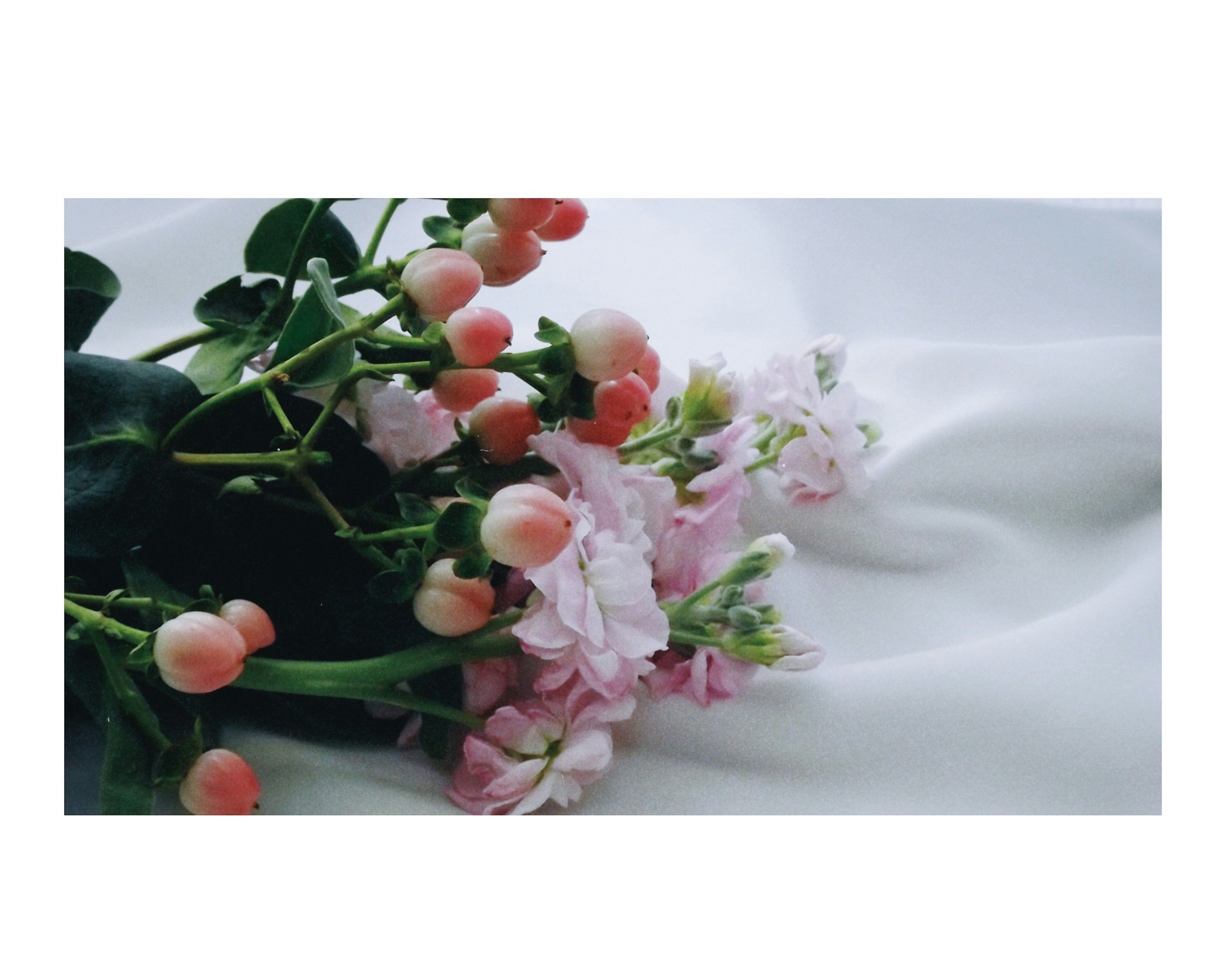 A bouquet of soft pink flowers on a smooth white fabric