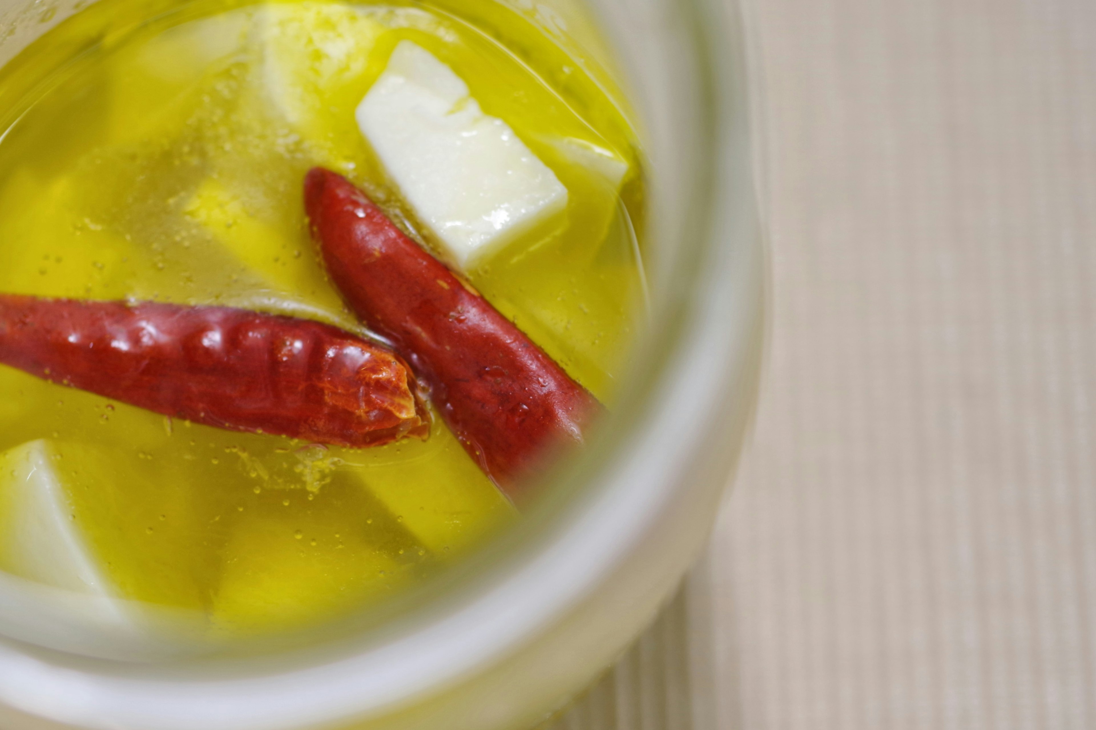 Close-up of a jar containing olive oil with red chili peppers and butter