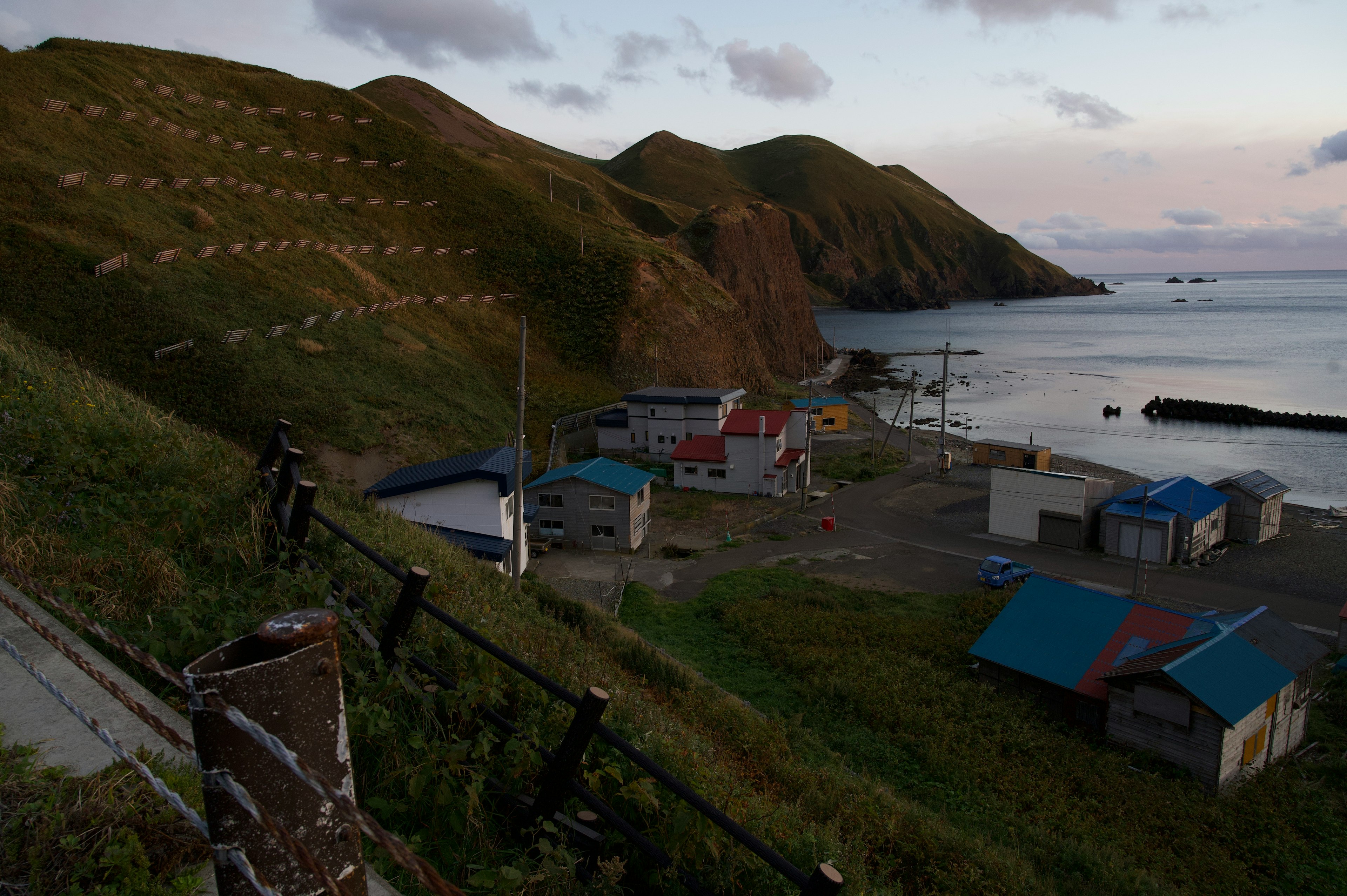 Coastal village with small structures and surrounding hills