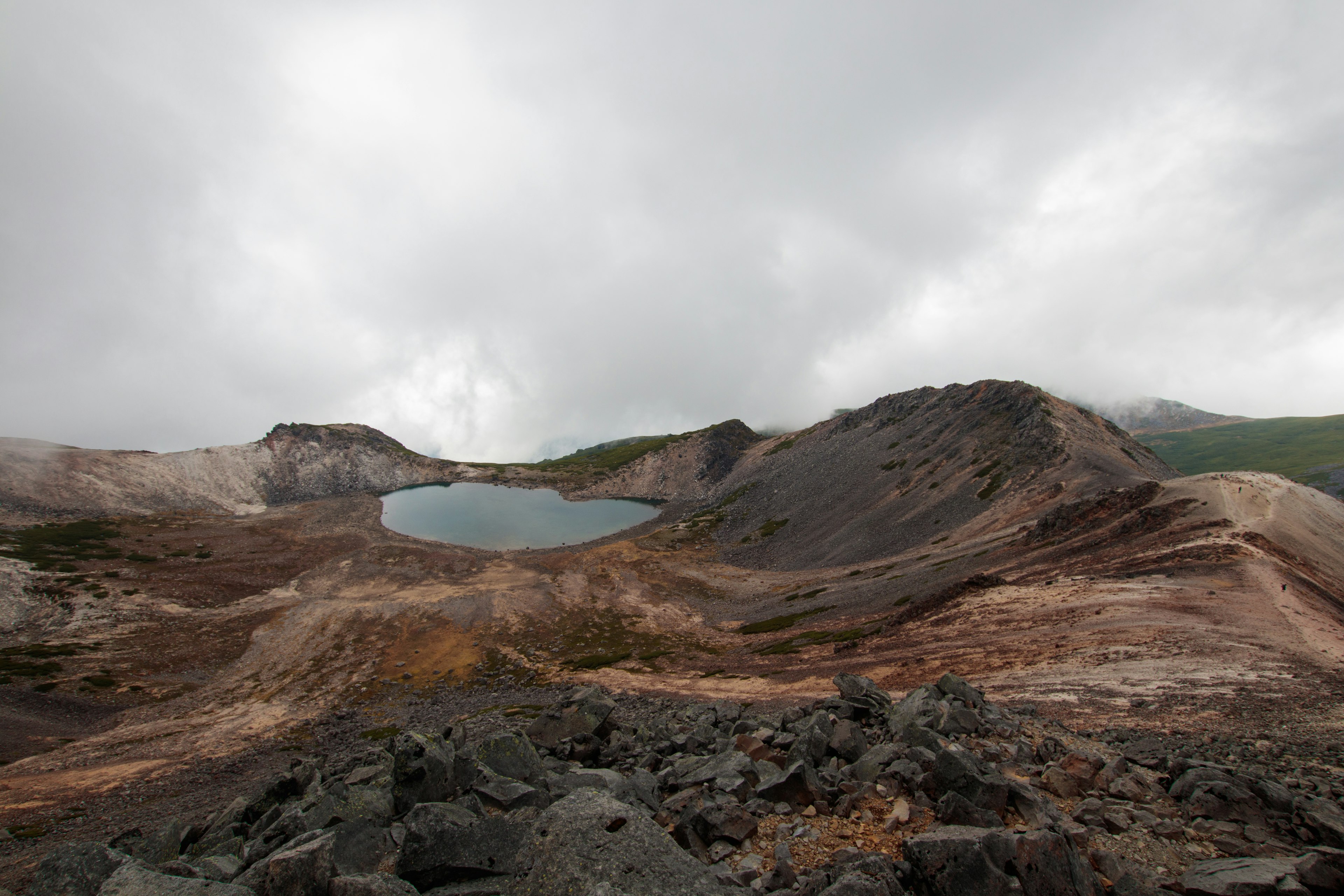 火山口的景观，有灰色岩石和一个水池