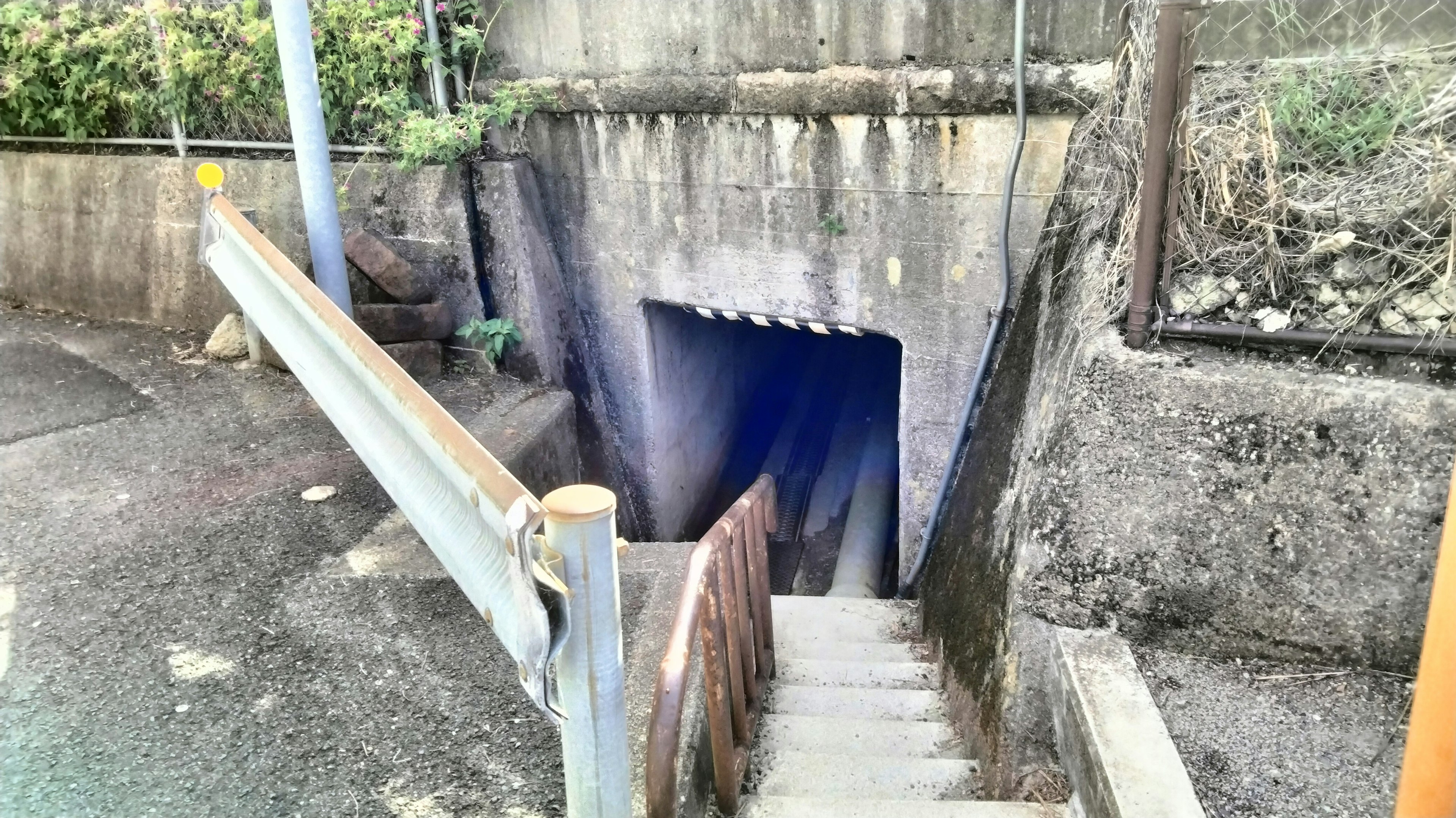 Entrada a un túnel oscuro con escaleras que bajan y paredes de concreto