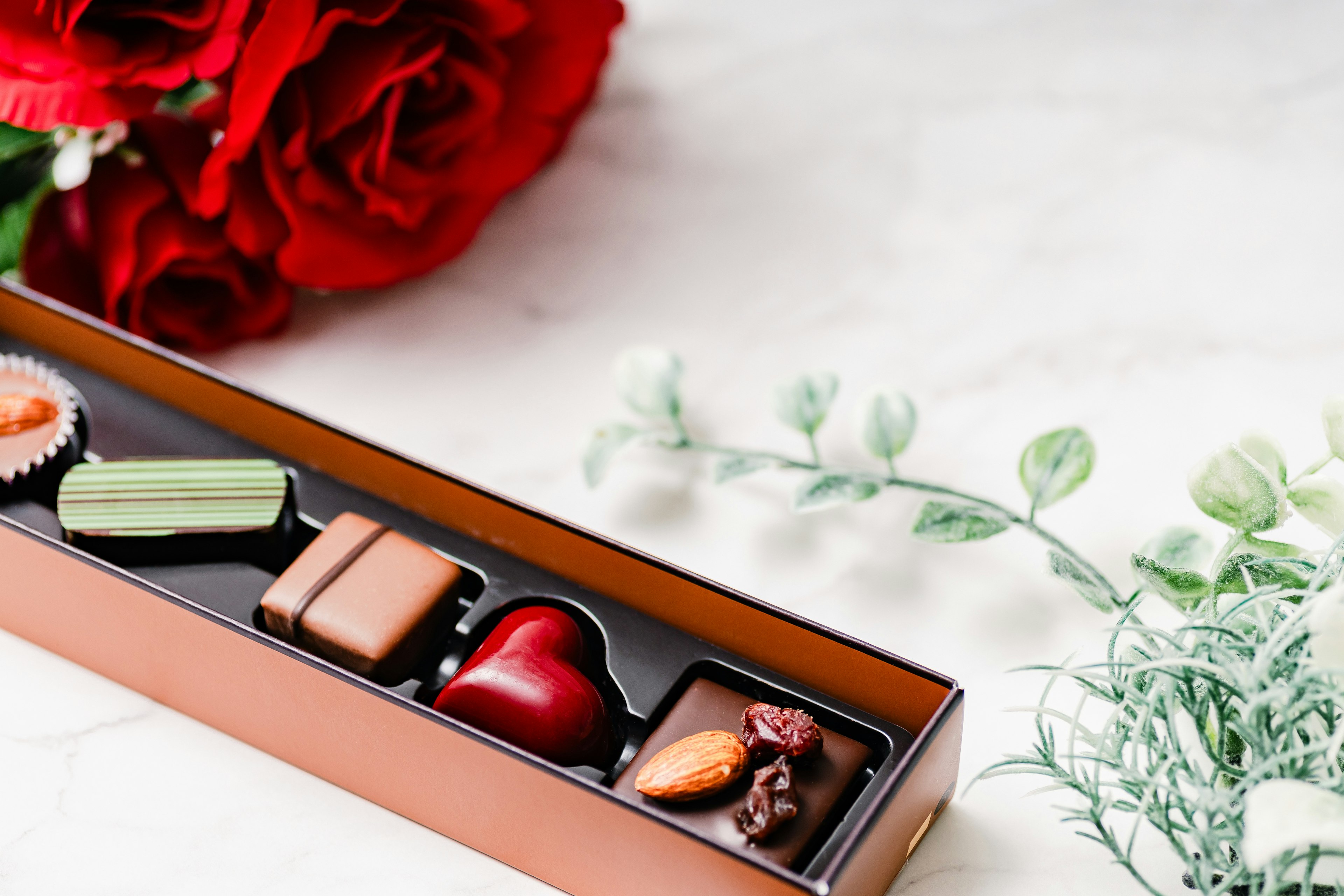 Un bel arrangement avec une boîte de chocolats à côté de roses rouges