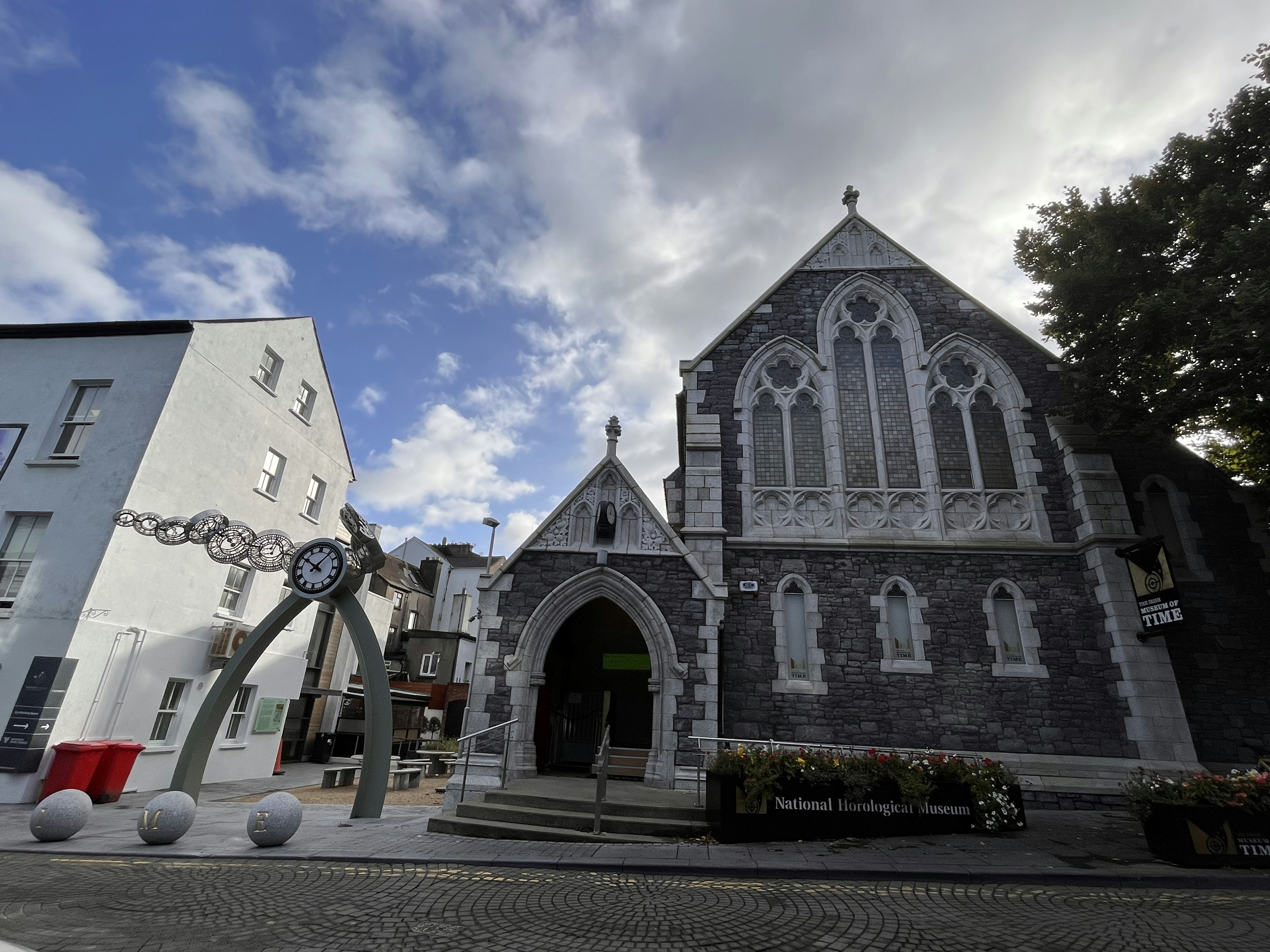 Grau steinerne Kirche mit gotischer Architektur und moderner Uhrenskulptur