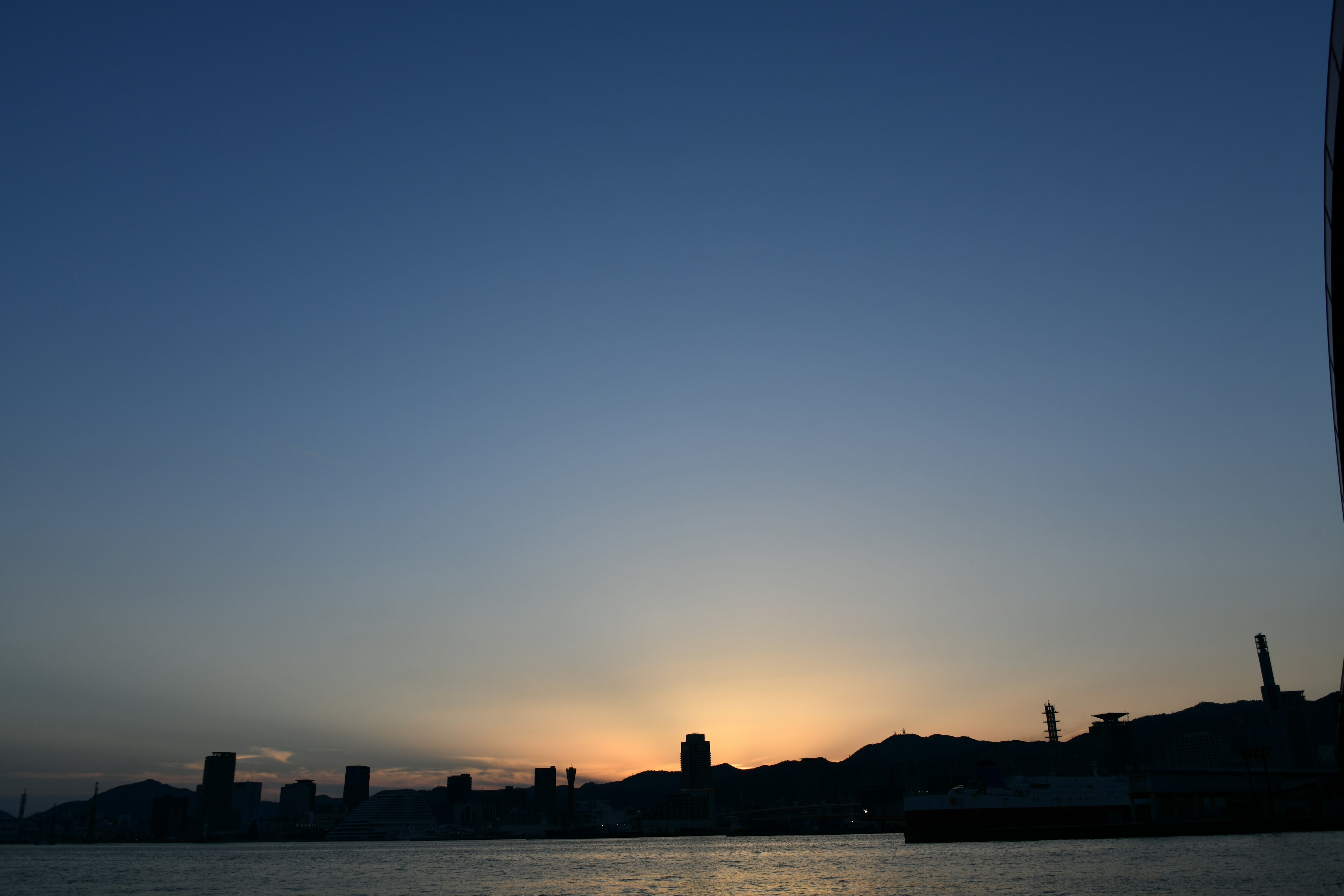 Sonnenuntergang über dem Meer mit silhouettiertem Stadtbild