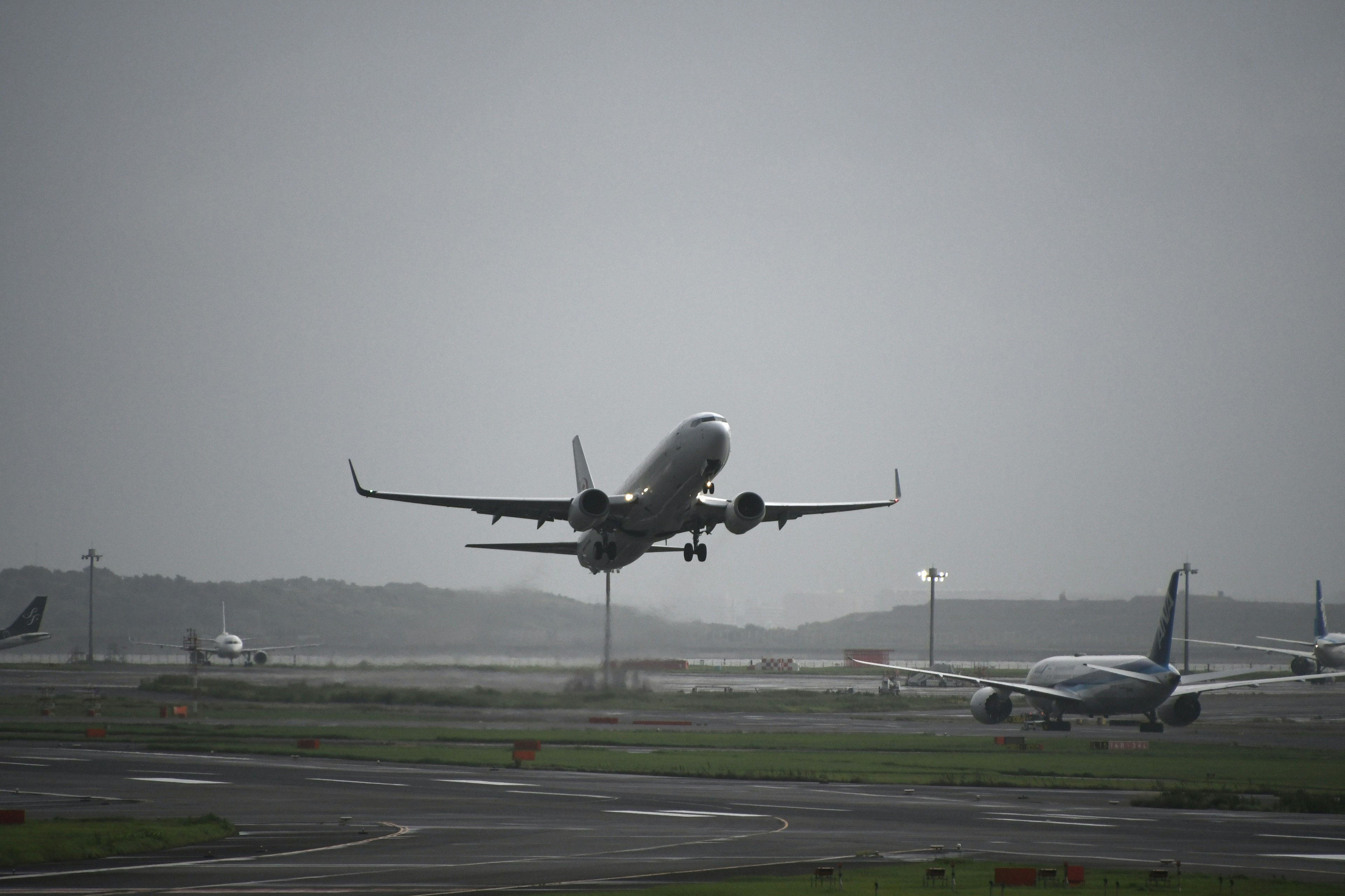 Silhouette di un aereo che decolla da un aeroporto sotto cieli nuvolosi