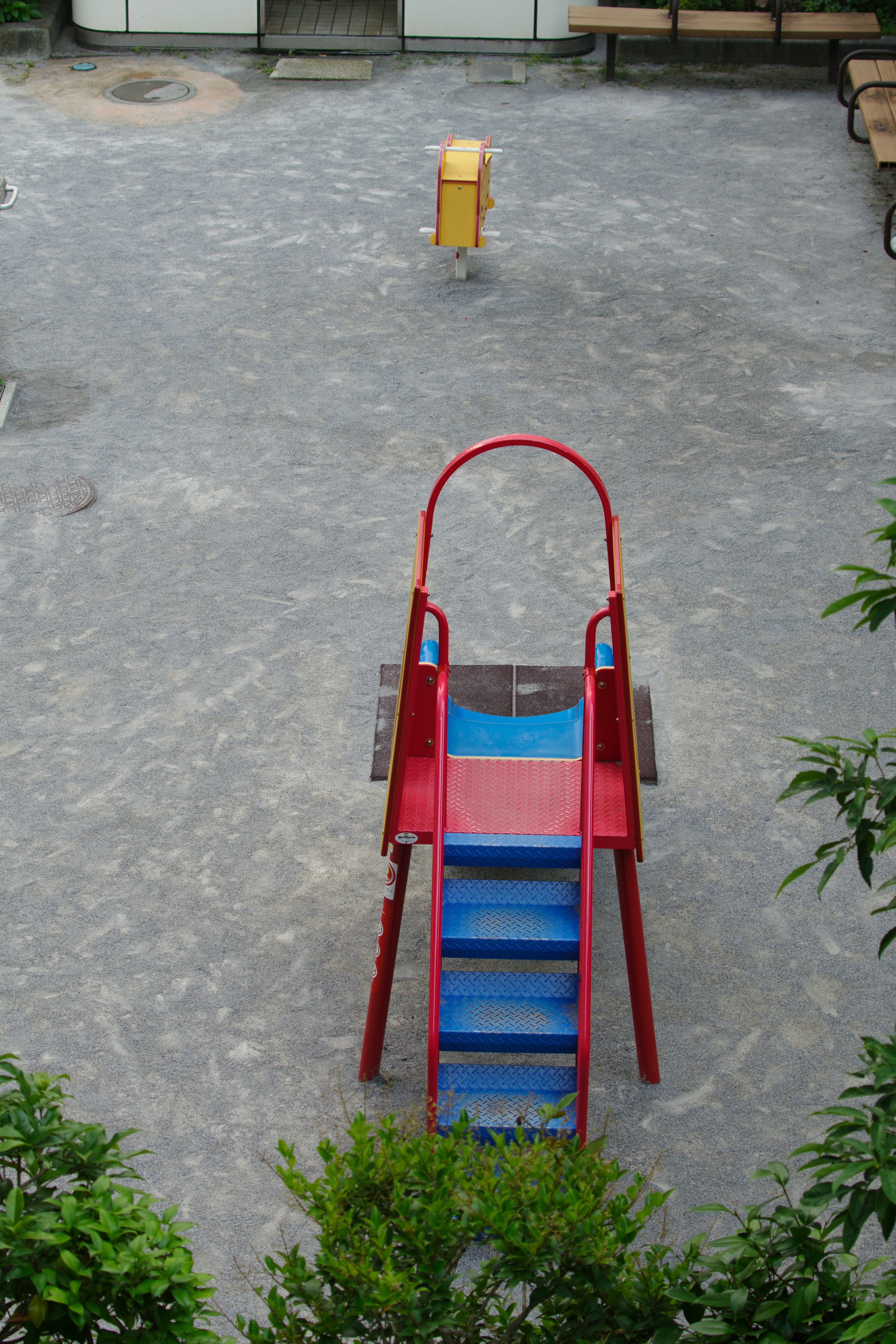 Escena de parque infantil con un tobogán rojo y azul