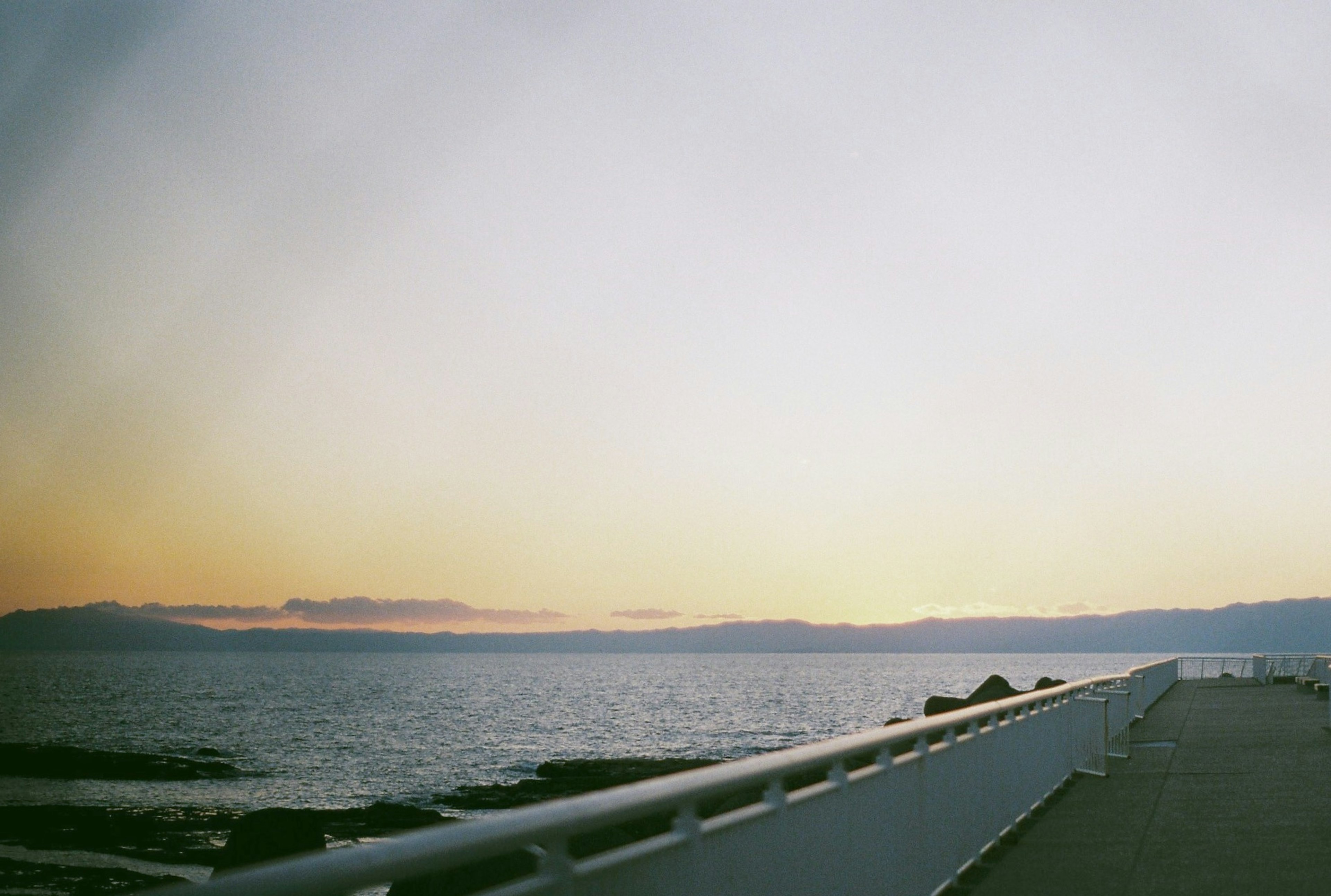 海辺の歩道が広がり、夕焼けの空が美しく広がっている