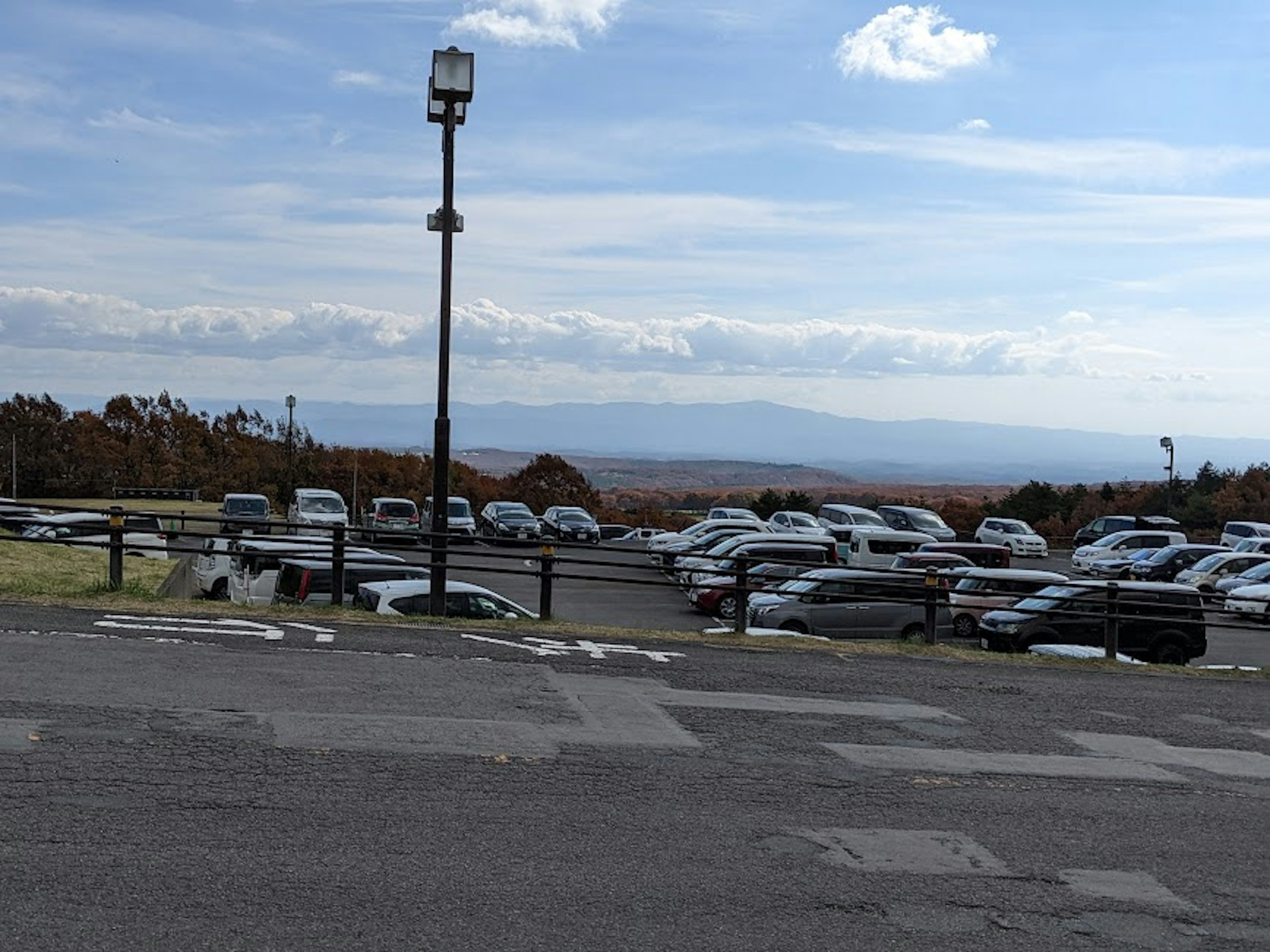 Tempat parkir yang dipenuhi banyak mobil dan pemandangan pegunungan yang indah