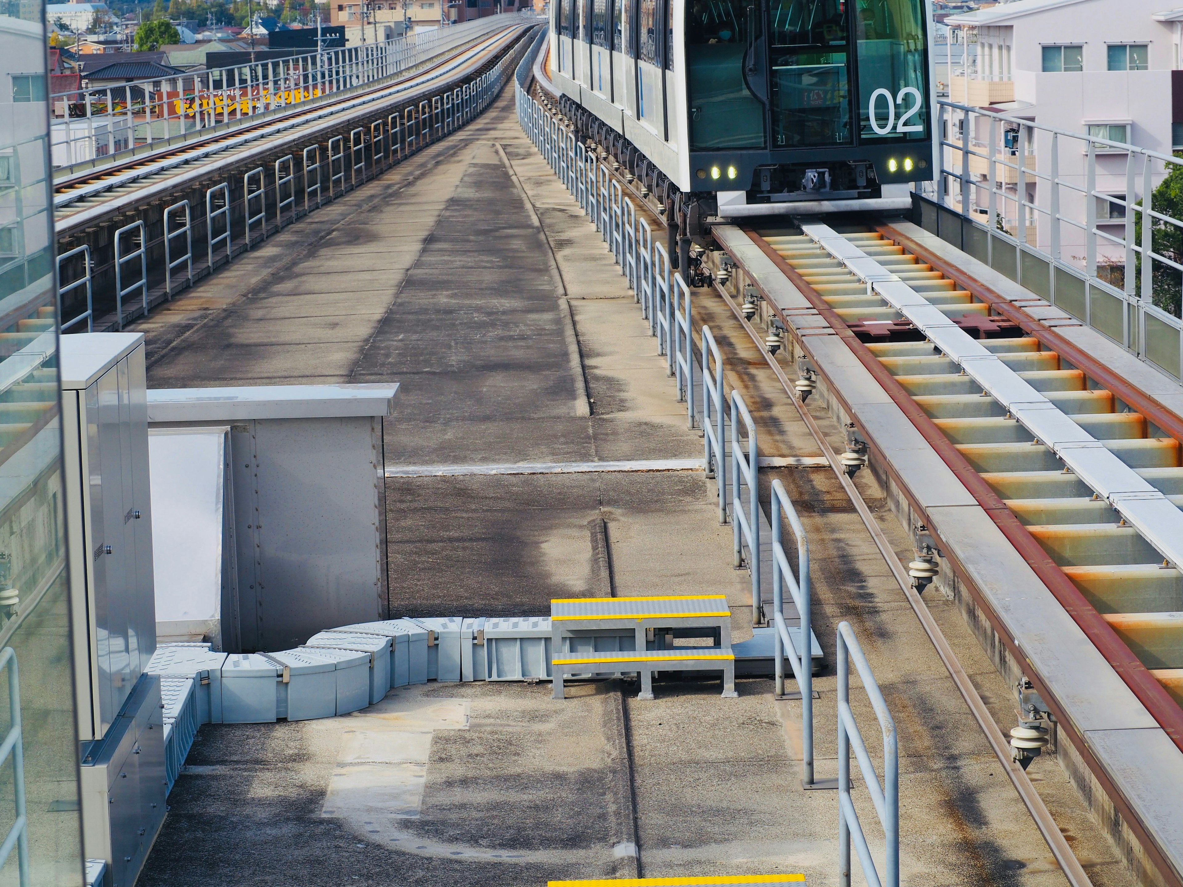 Blick auf erhöhte Eisenbahngleise und einen Zug, der sich einer Station nähert