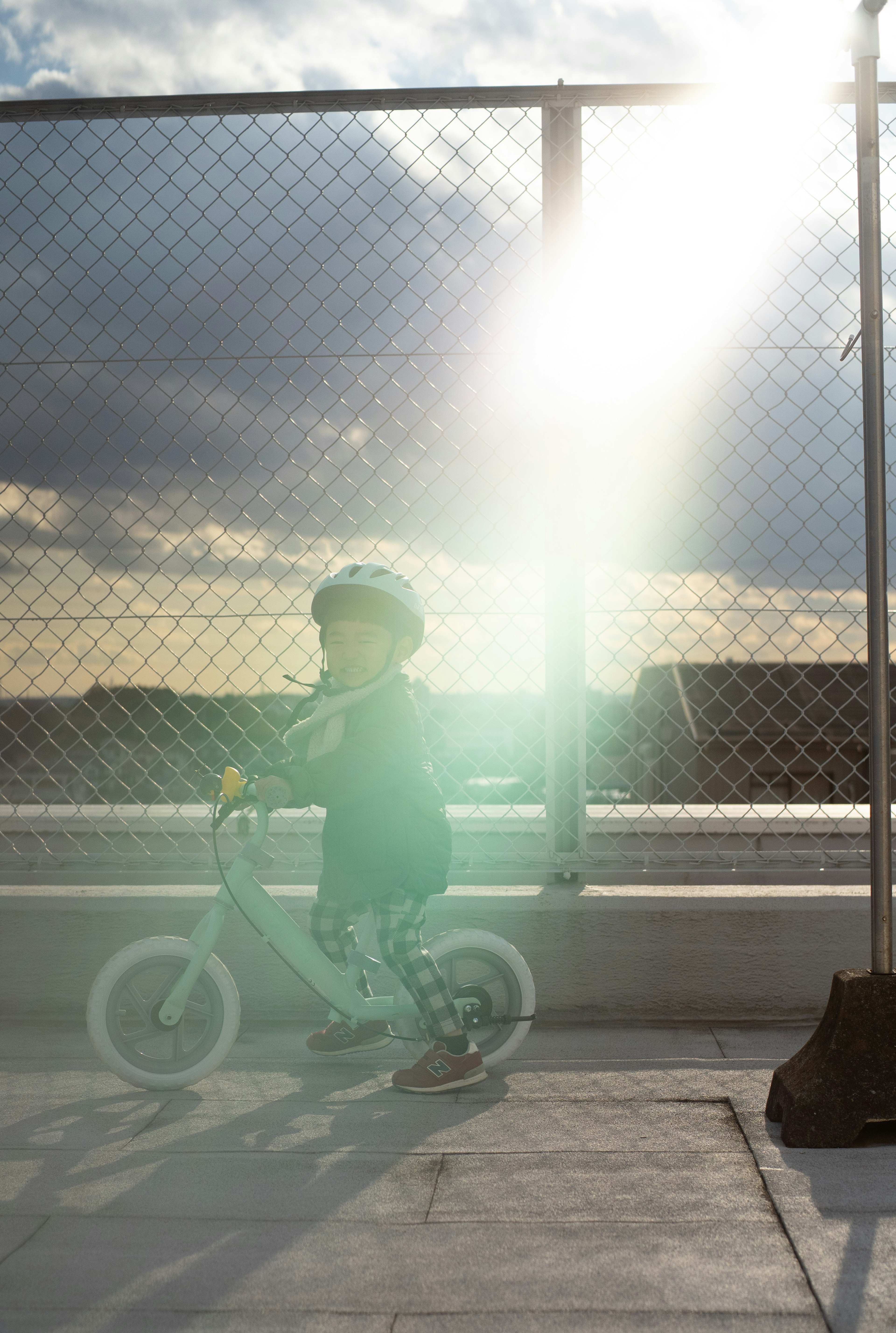 Enfant faisant du vélo d'équilibre avec des reflets de soleil au coucher du soleil