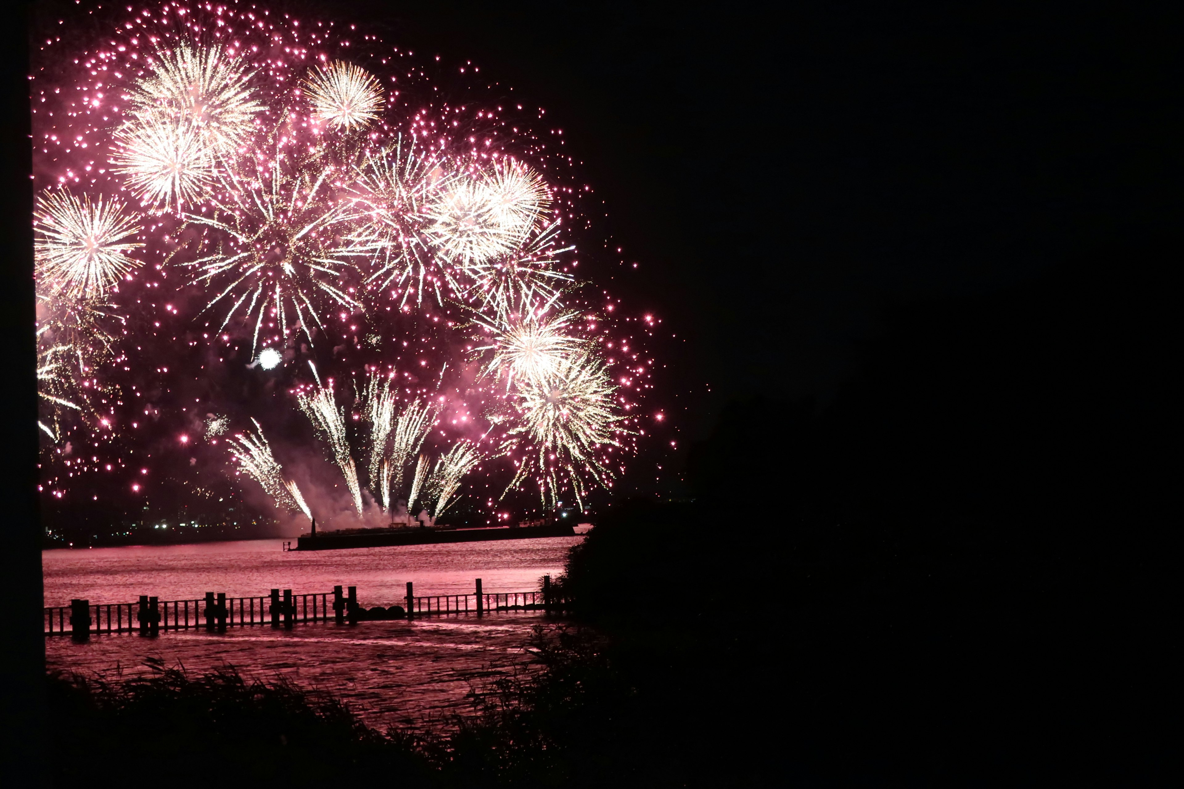 Colorful fireworks blooming in the night sky reflecting beautifully on the water