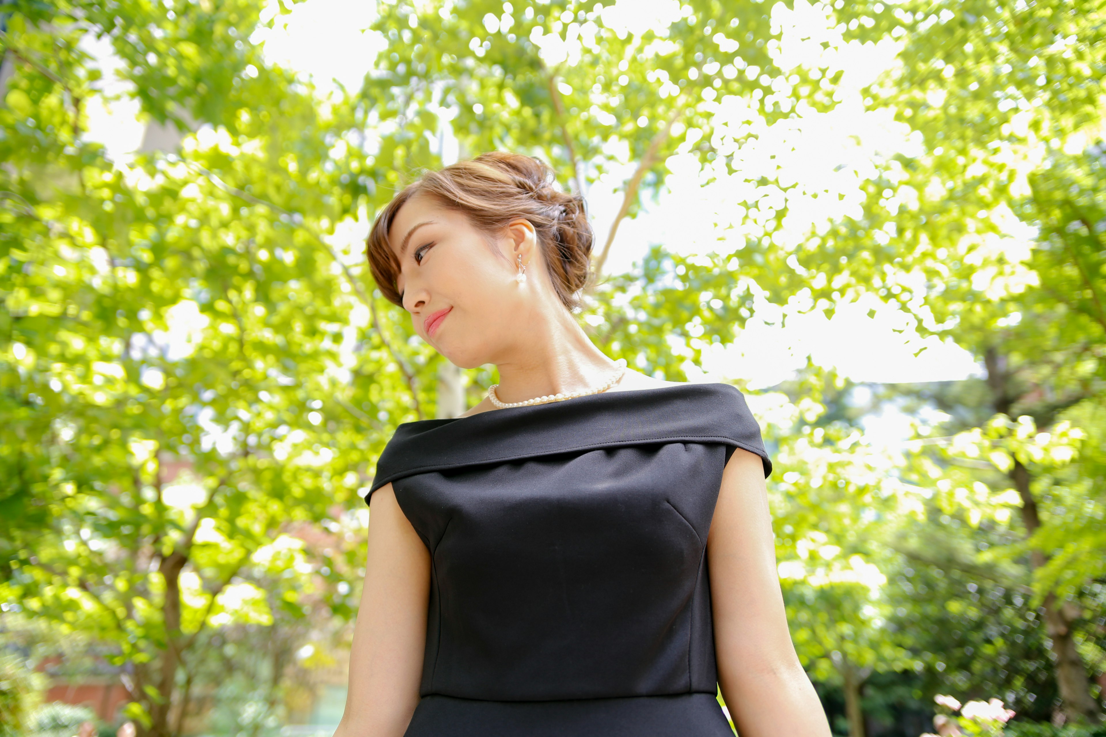 Una mujer con un vestido negro sonriendo frente a un fondo verde