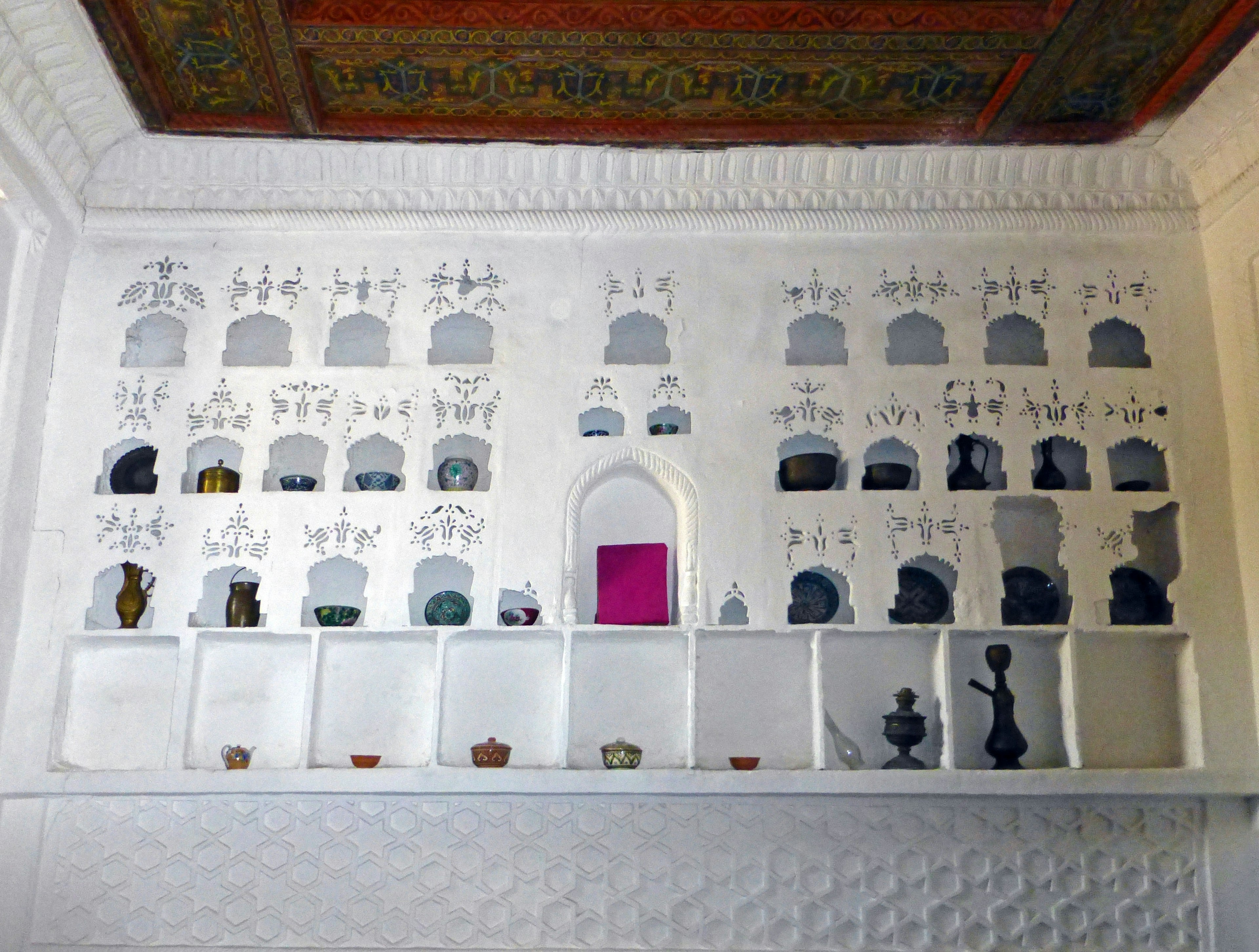 A wall display featuring diverse objects on white shelves with a colorful ceiling