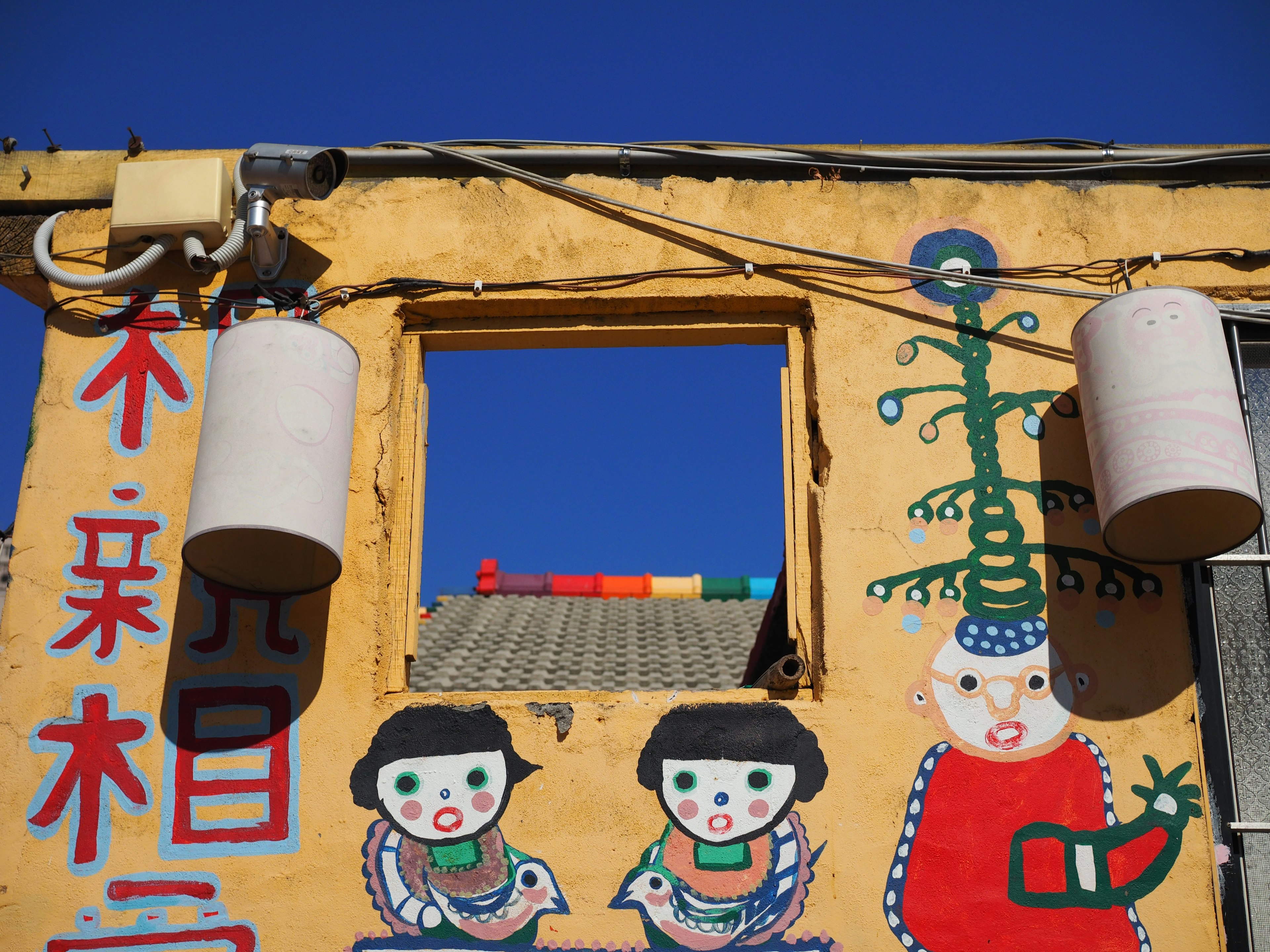 Fresque colorée représentant des enfants et des lanternes sur un mur jaune