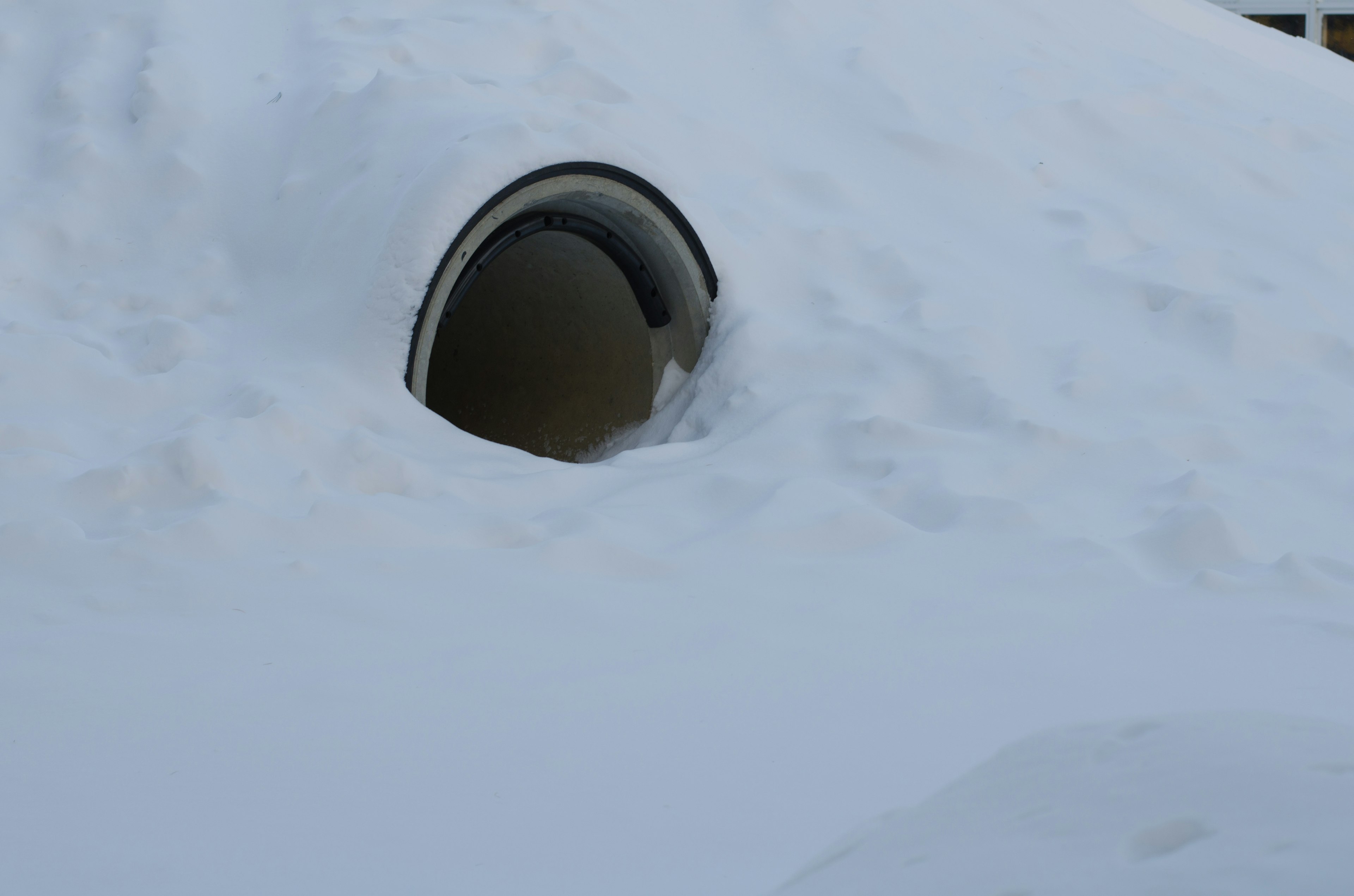 A circular window partially buried in snow