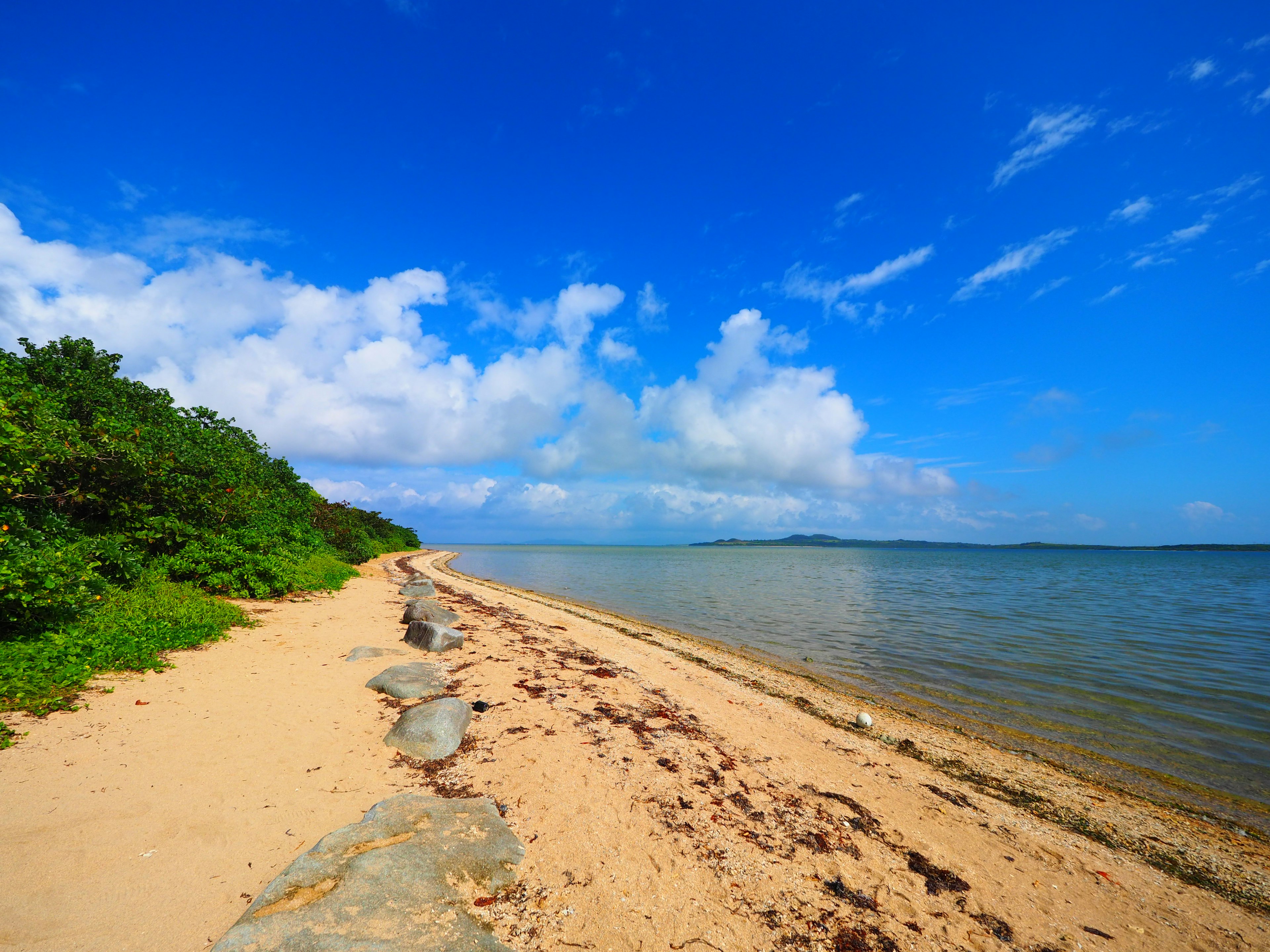 ทิวทัศน์ชายหาดที่สวยงามท้องฟ้าสีฟ้าและมหาสมุทรชายหาดทรายพร้อมก้อนหิน