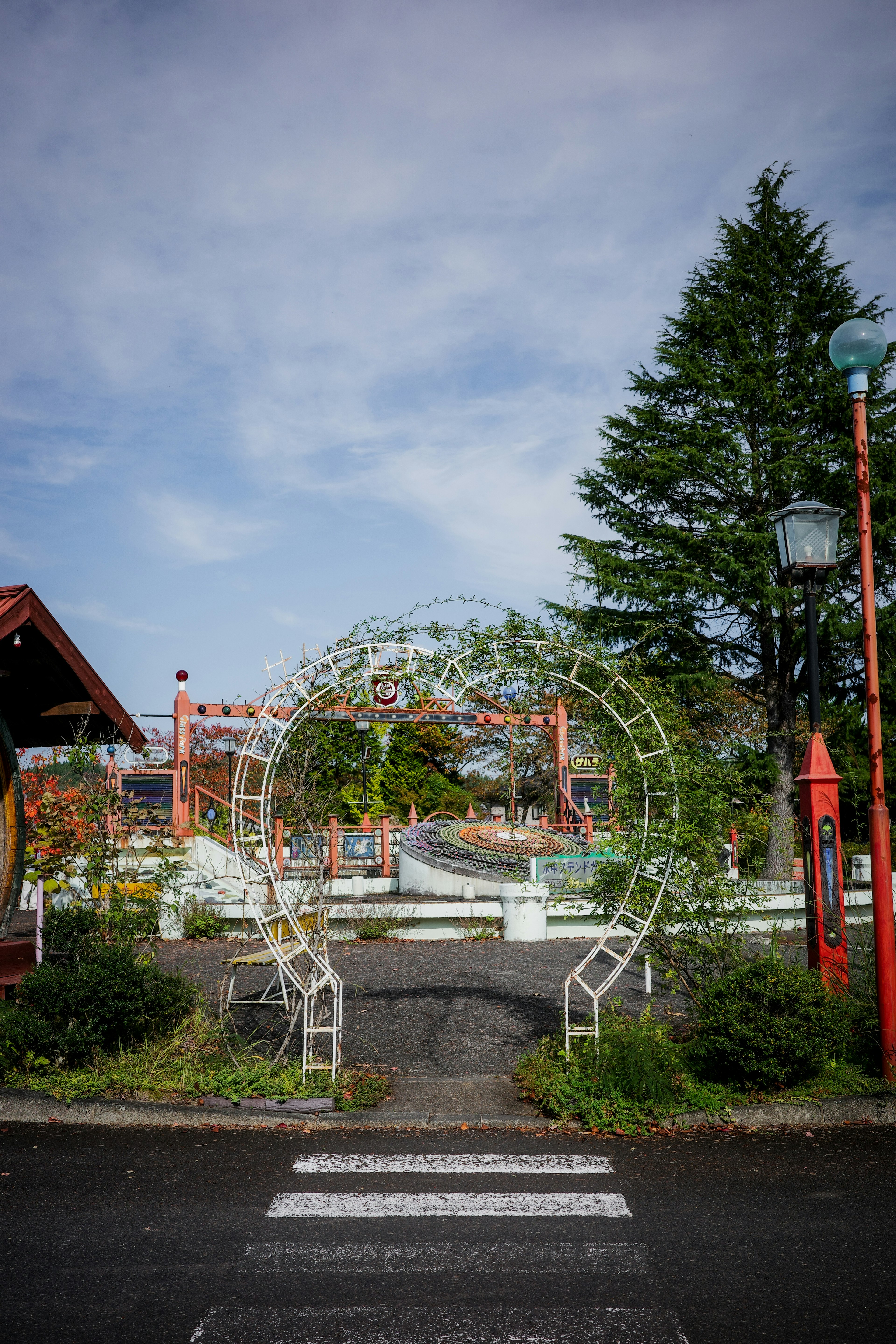 白いアーチの門と緑の木々がある公園の入り口