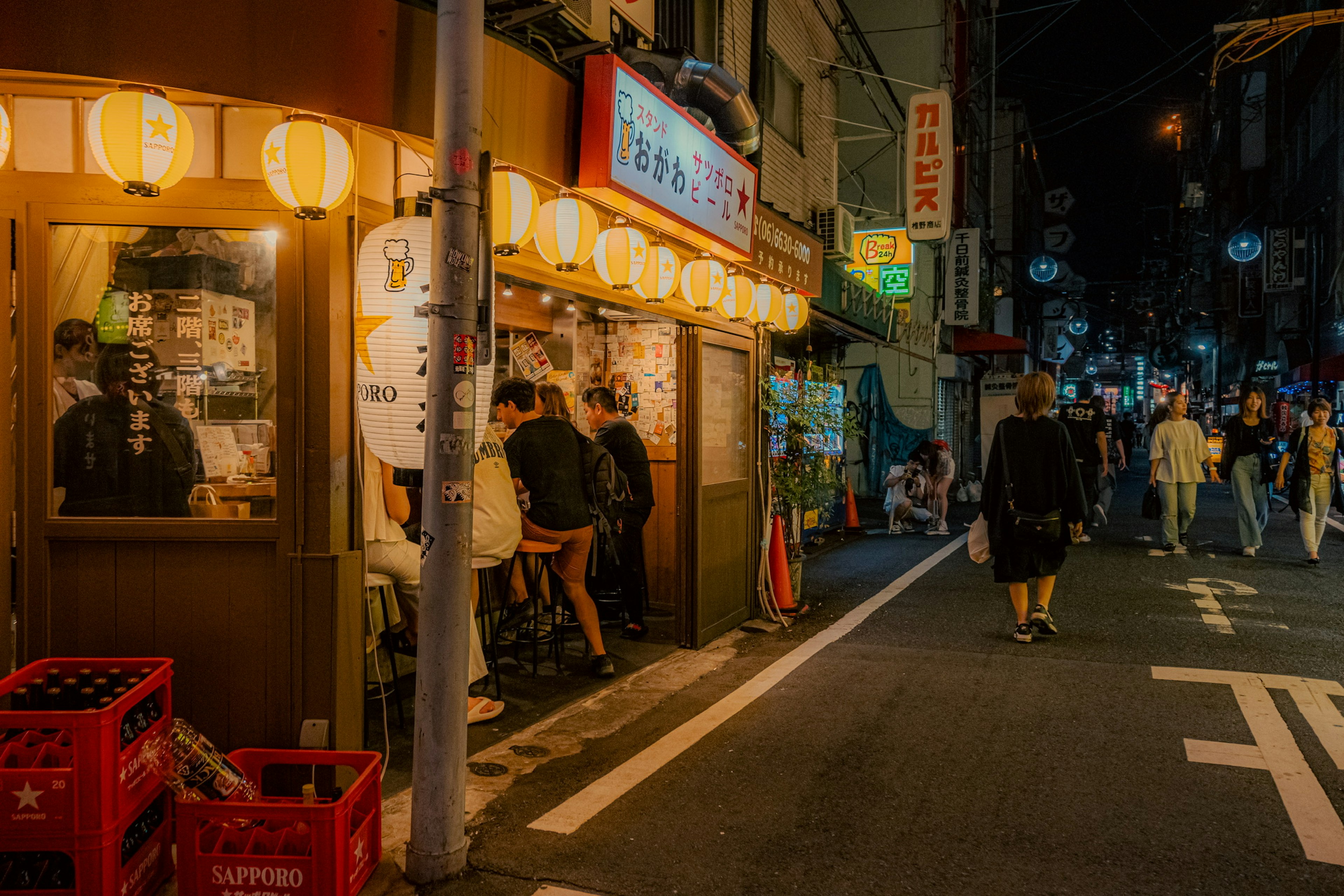 Nächtliche Szene einer Straße in Tokio mit beleuchteten Restaurants und Menschen