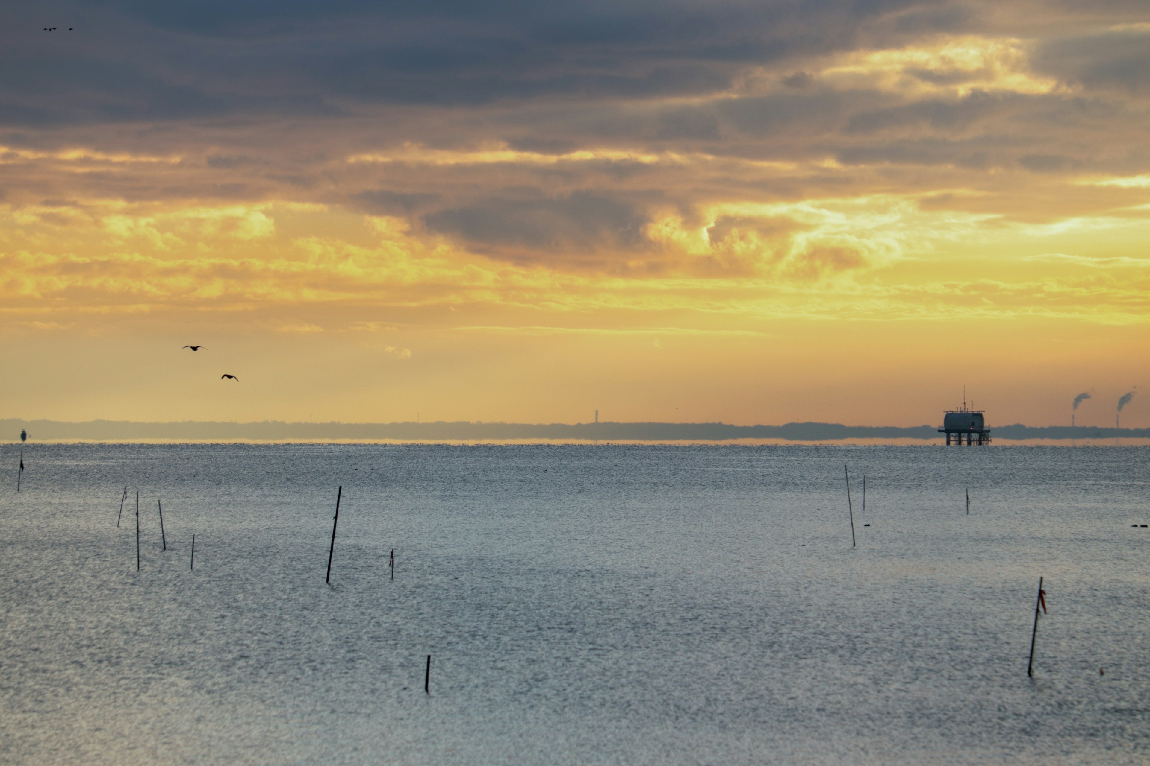 Paesaggio marino sereno al tramonto con una capanna da pesca in lontananza