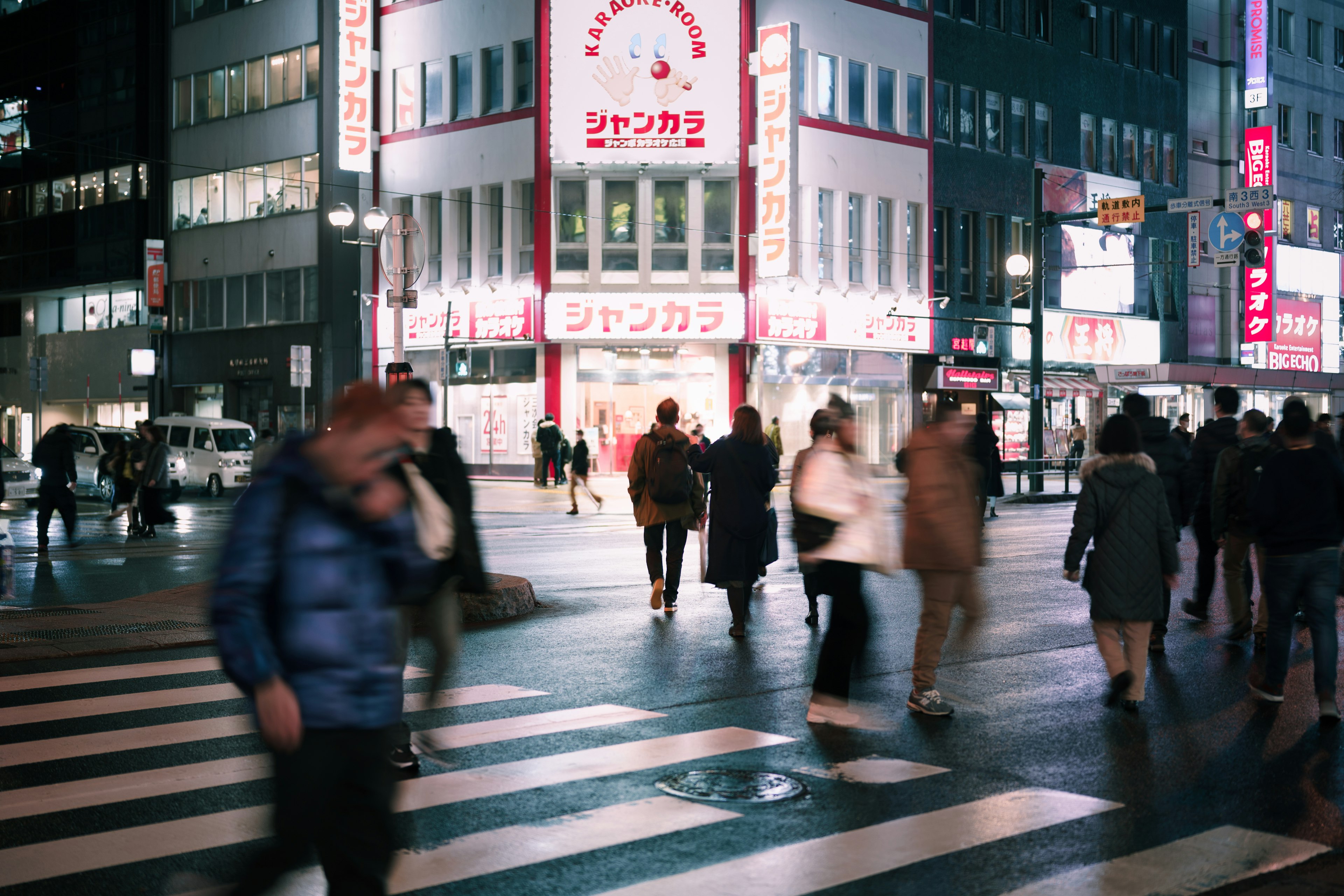 Busy intersection with pedestrians and bright signage in an urban setting