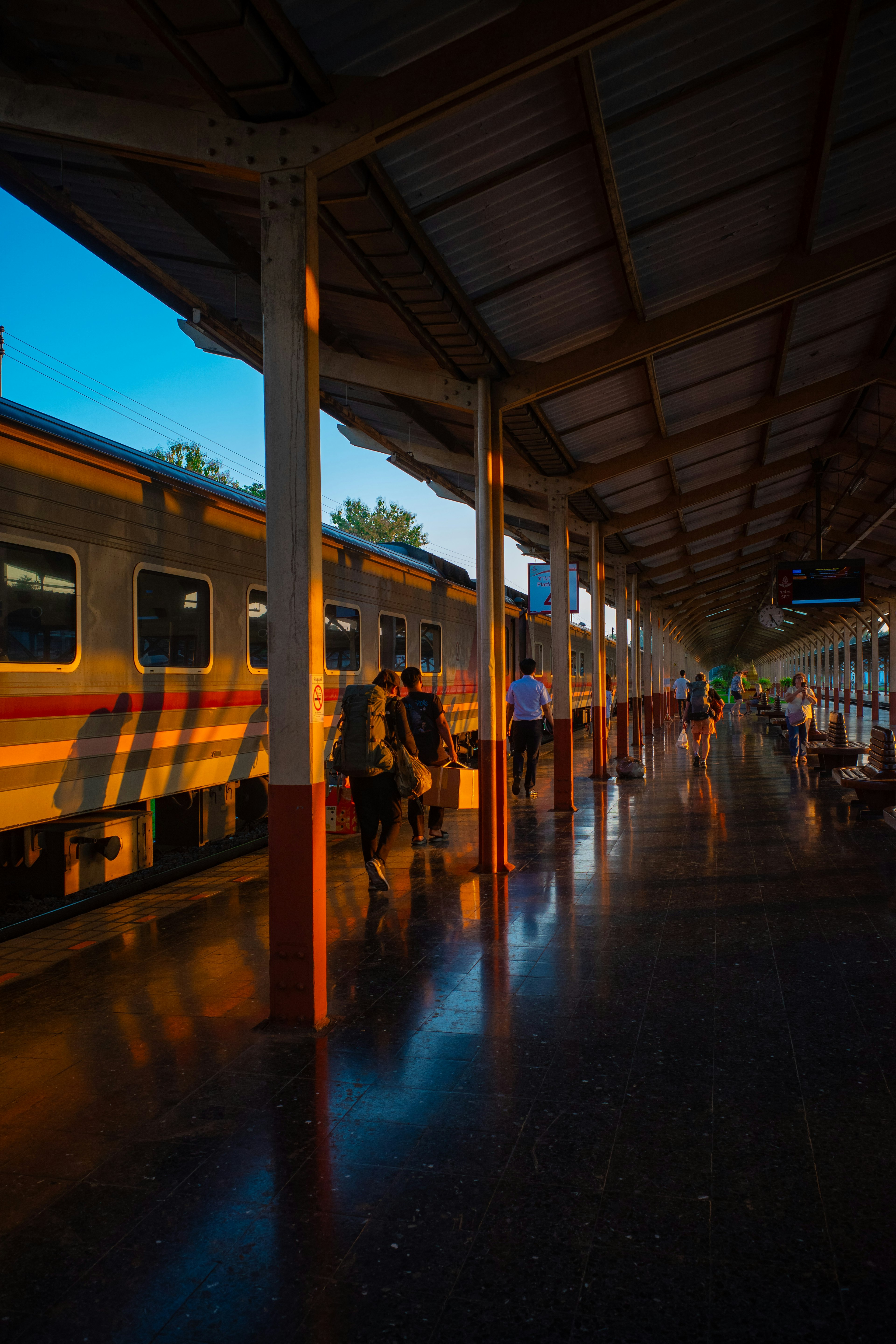 ฉากพระอาทิตย์ตกที่สถานีรถไฟมีผู้โดยสารและรถไฟ