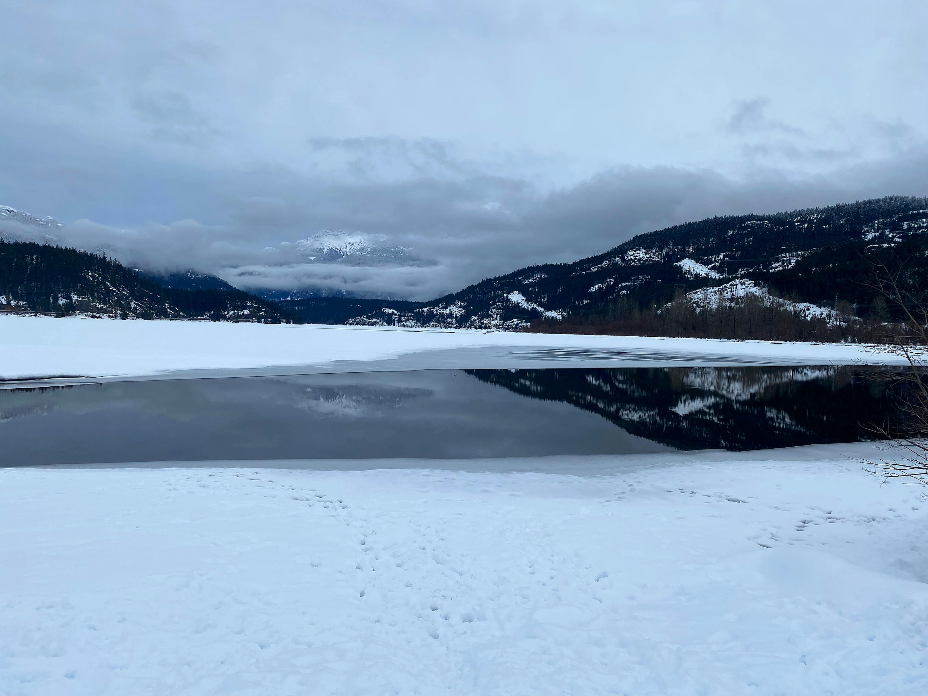 雪に覆われた湖と山々の反射が見える冬の風景