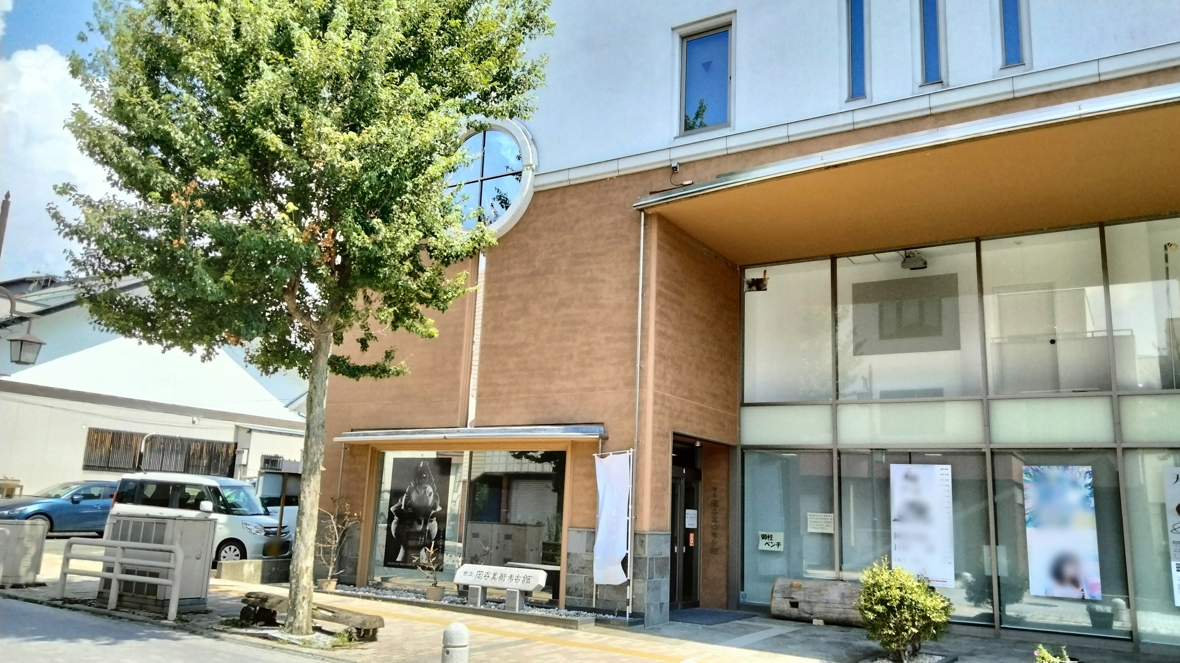 Edificio moderno con grandes ventanas y un árbol verde bajo la luz brillante del sol