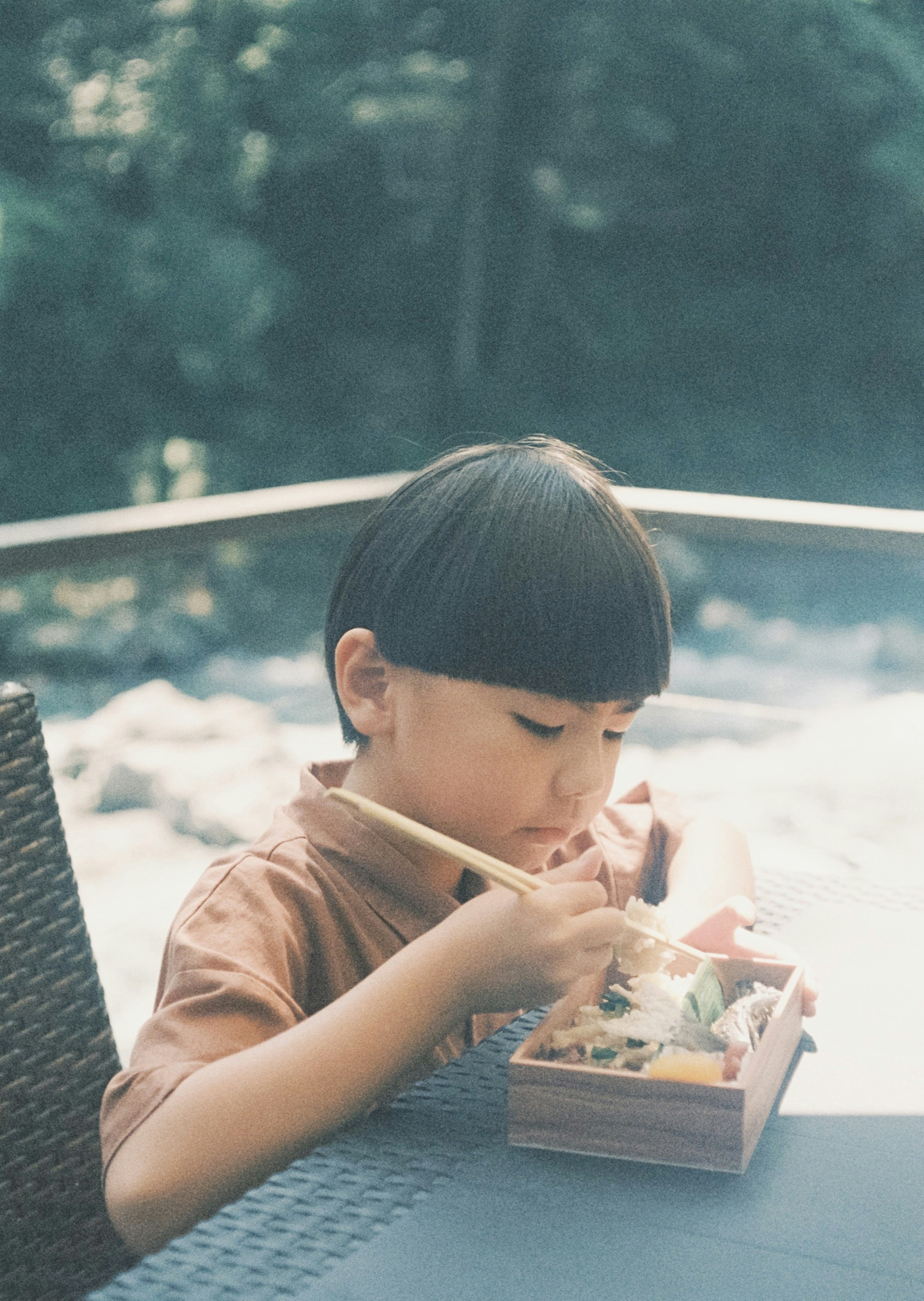 Un enfant dégustant une boîte à bento dans un cadre naturel