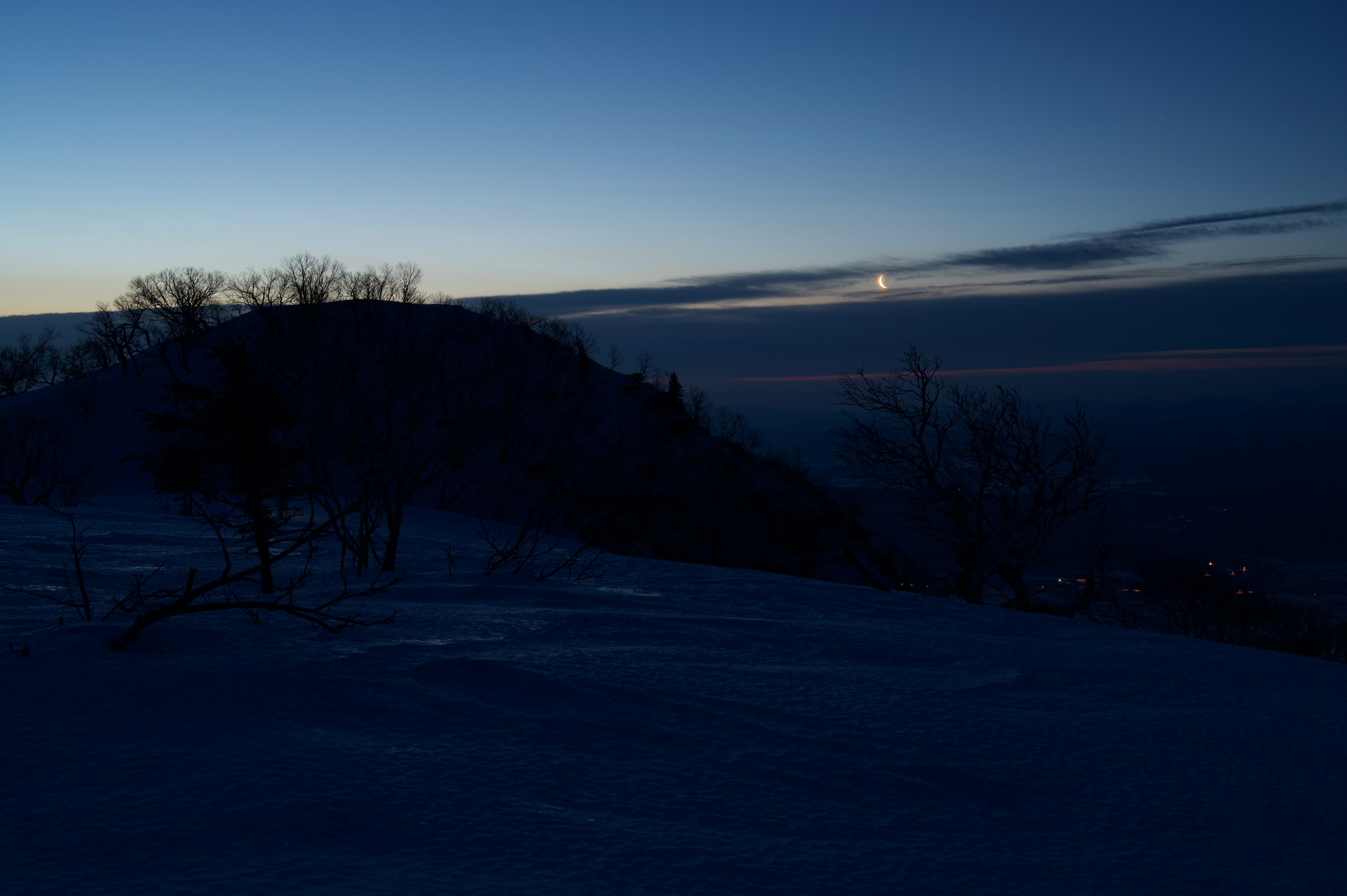 雪に覆われた丘の夜明けの風景 月が空に浮かんでいる