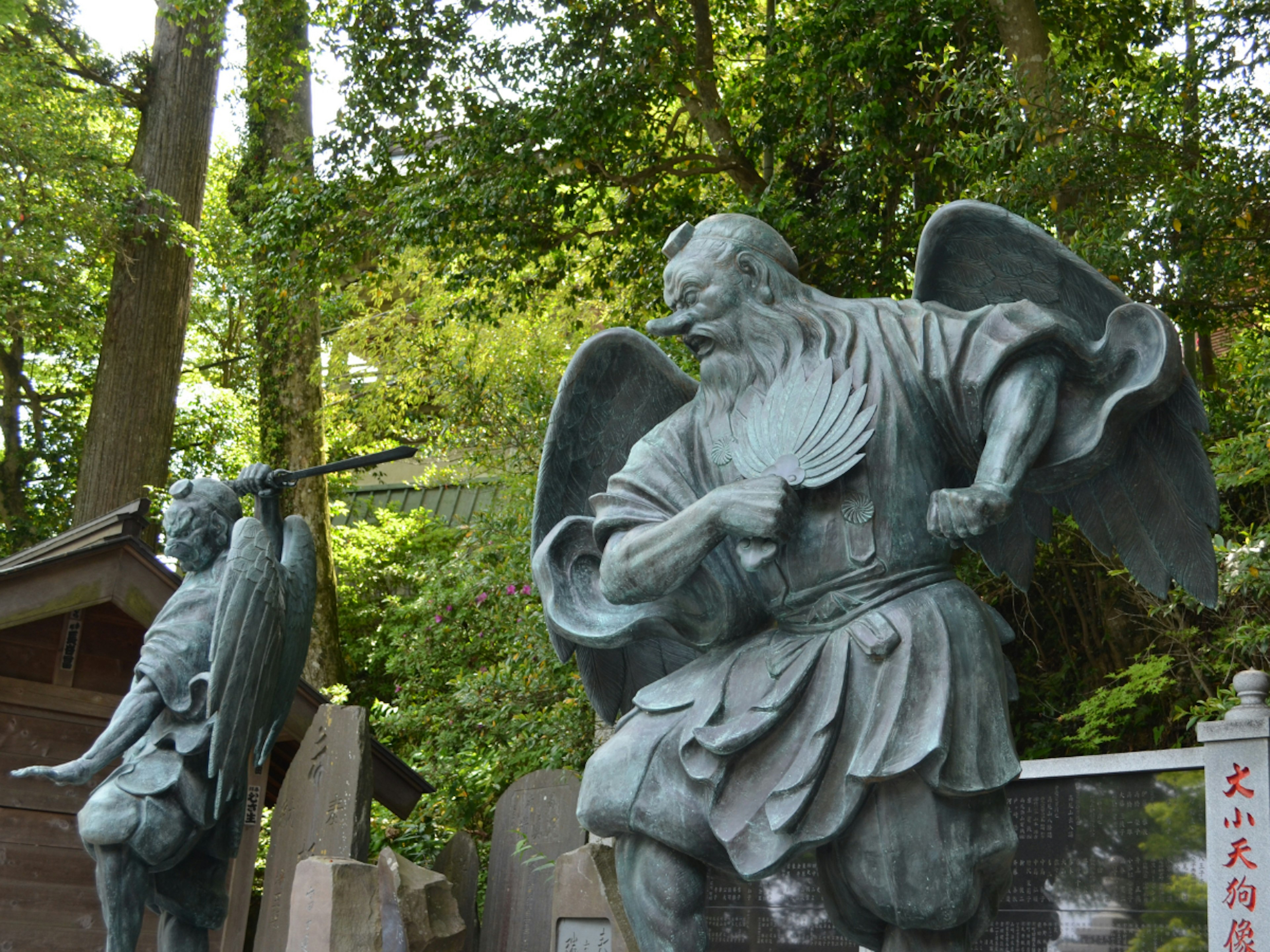 Deux statues en bronze près d'un sanctuaire, un homme avec des ailes à gauche, un homme armé à droite