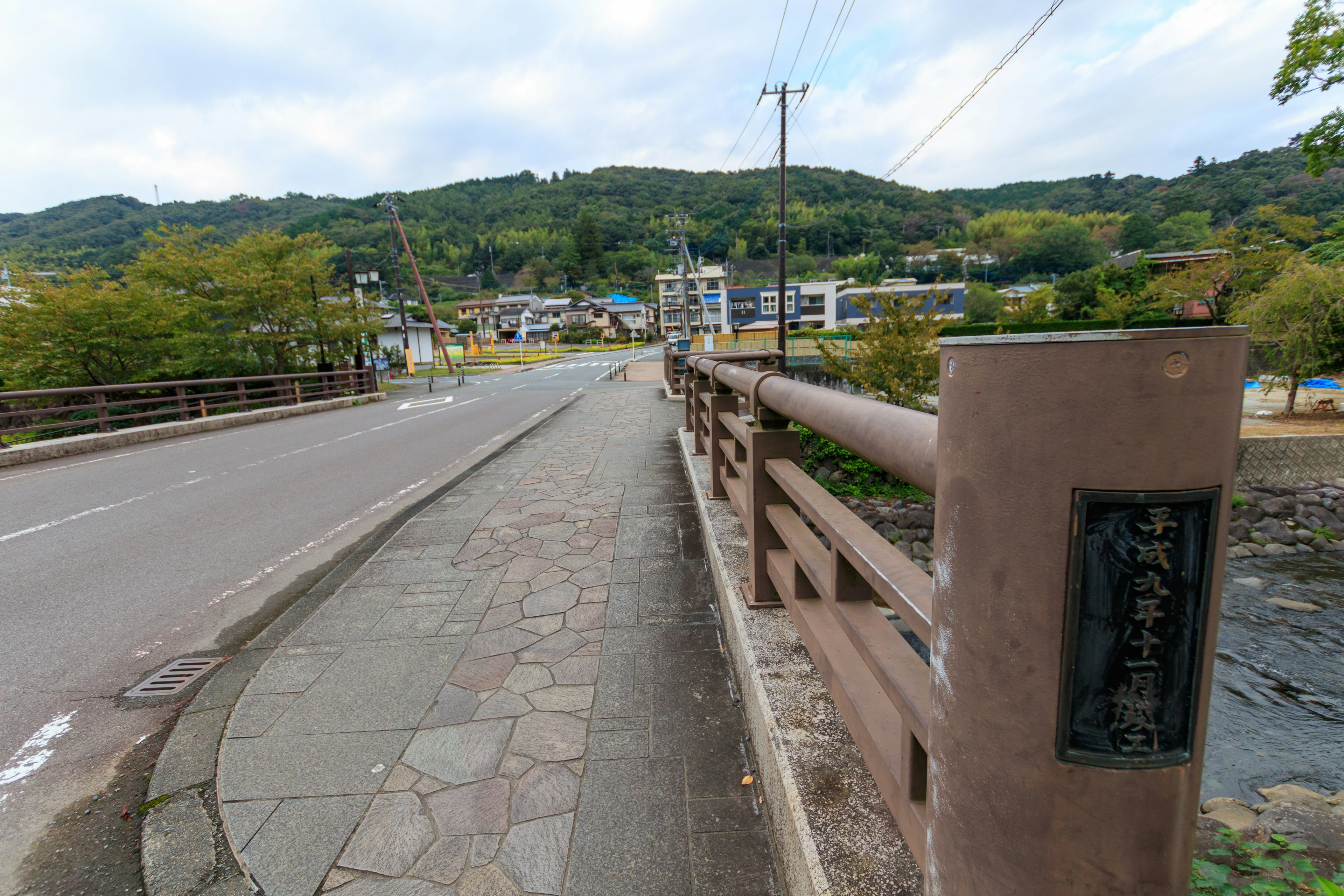 Blick auf eine Brücke und eine Straße mit grünen Hügeln und Gebäuden im Hintergrund