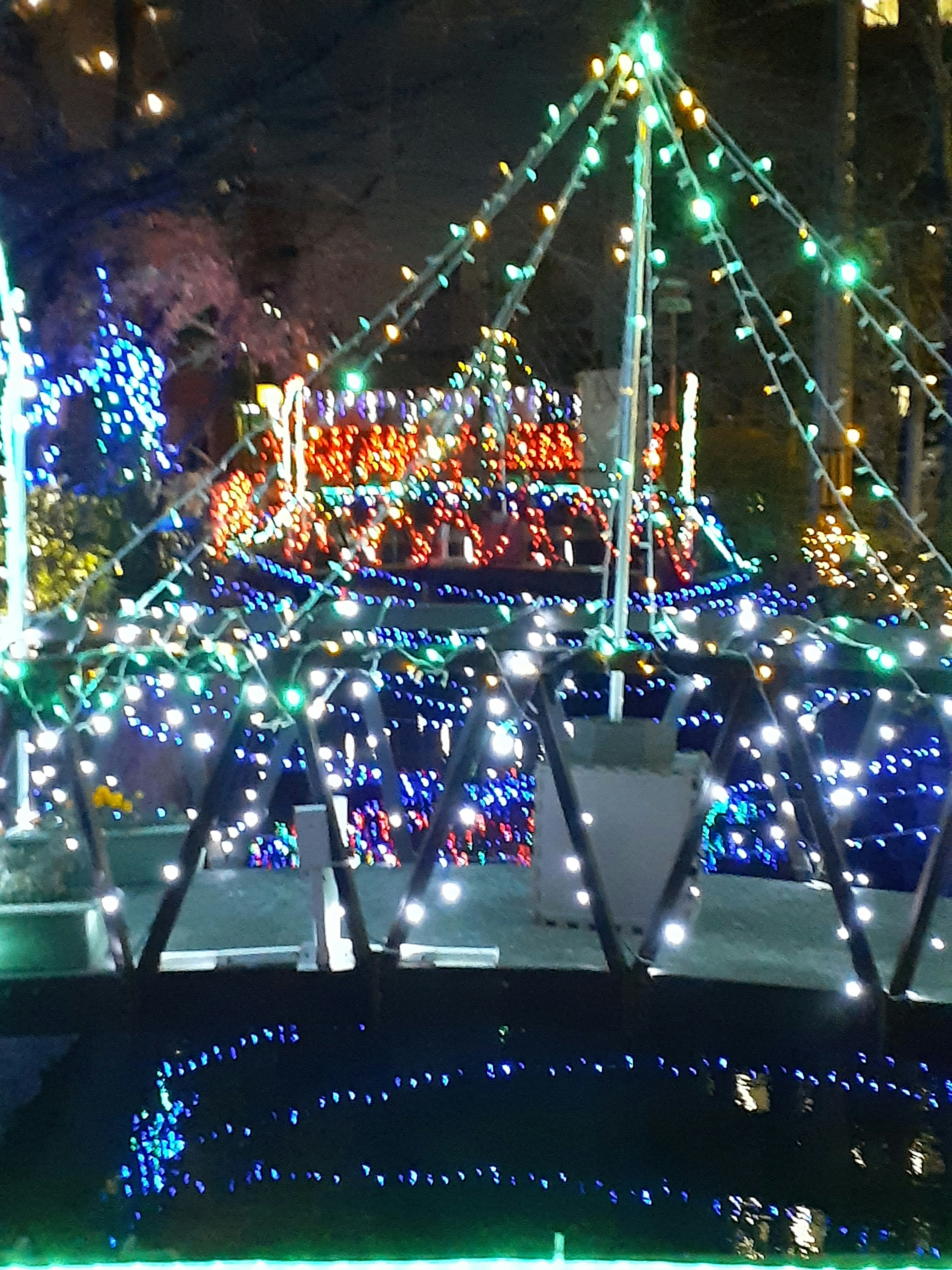 Bridge adorned with colorful lights at night reflecting in the water