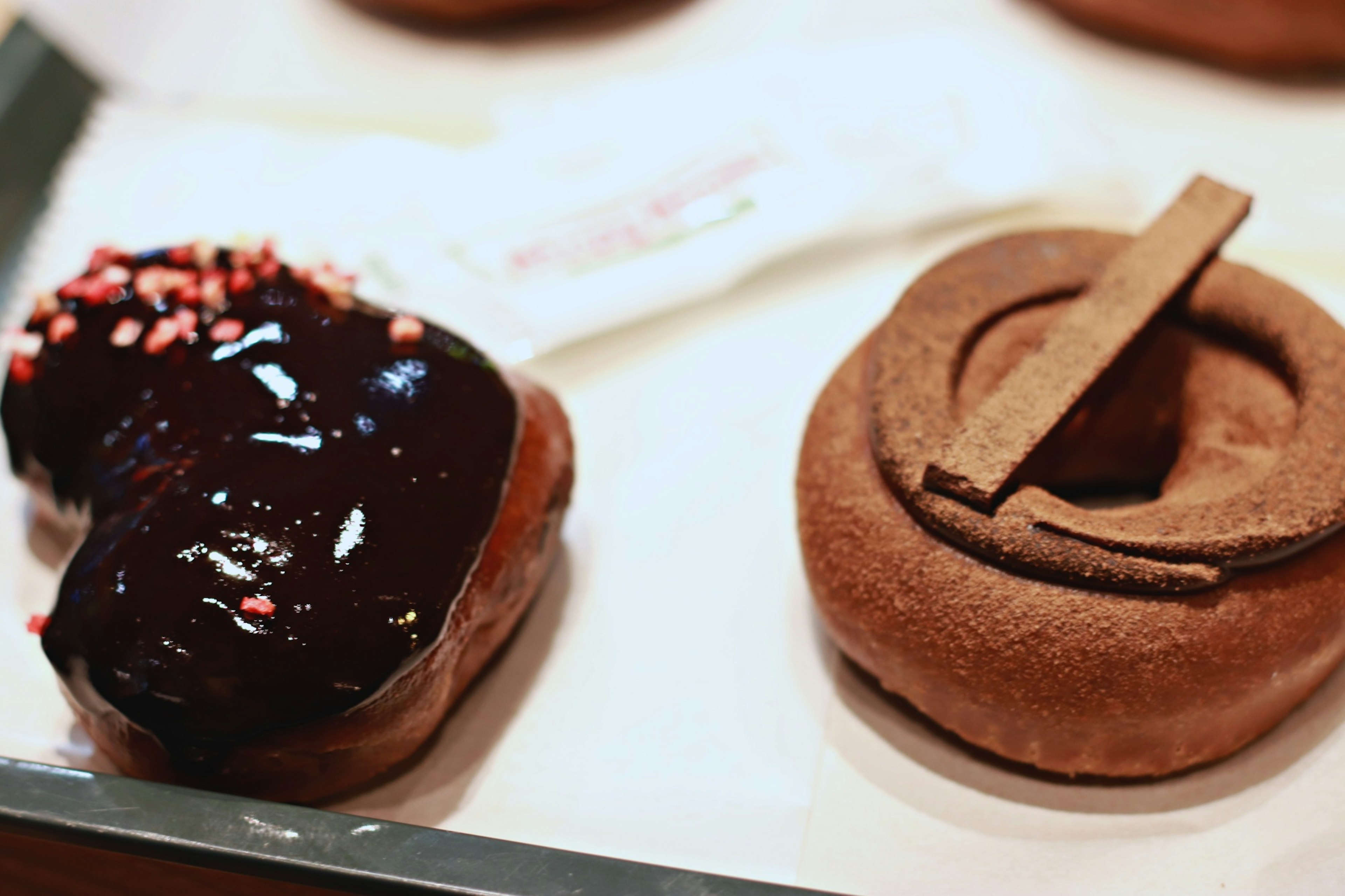 A plate with a chocolate glazed heart-shaped donut and a simple brown donut