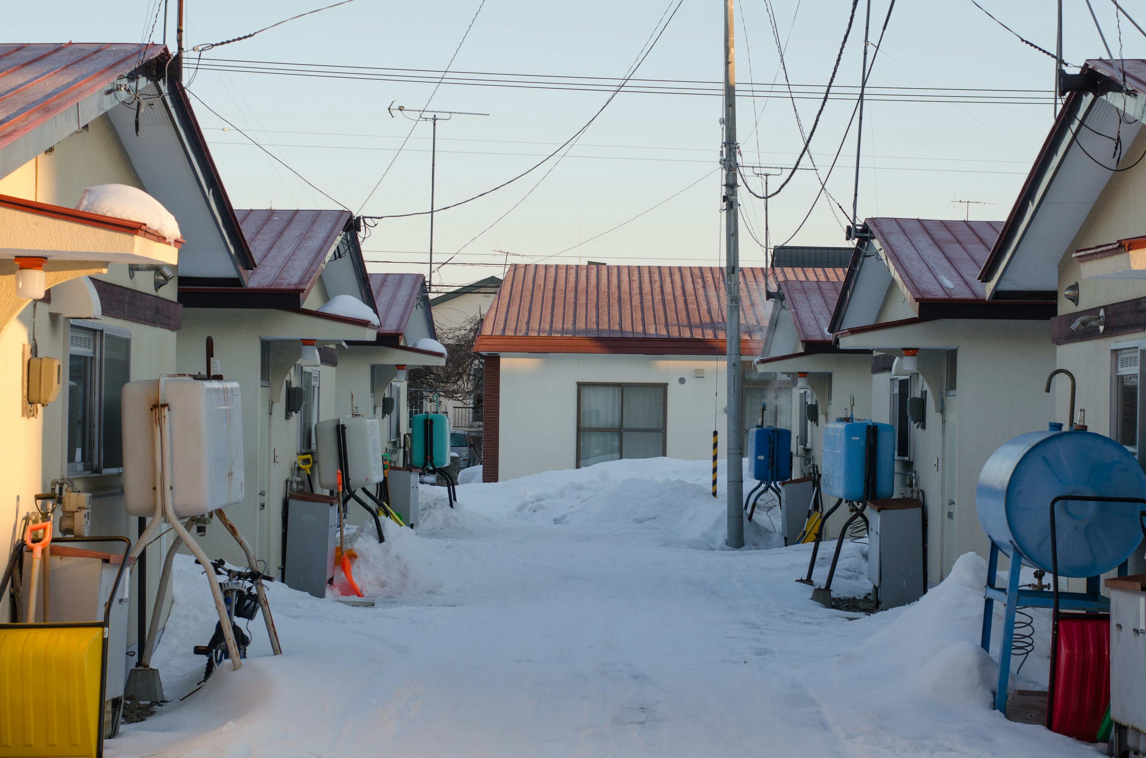 Snow-covered residential street with houses and power lines