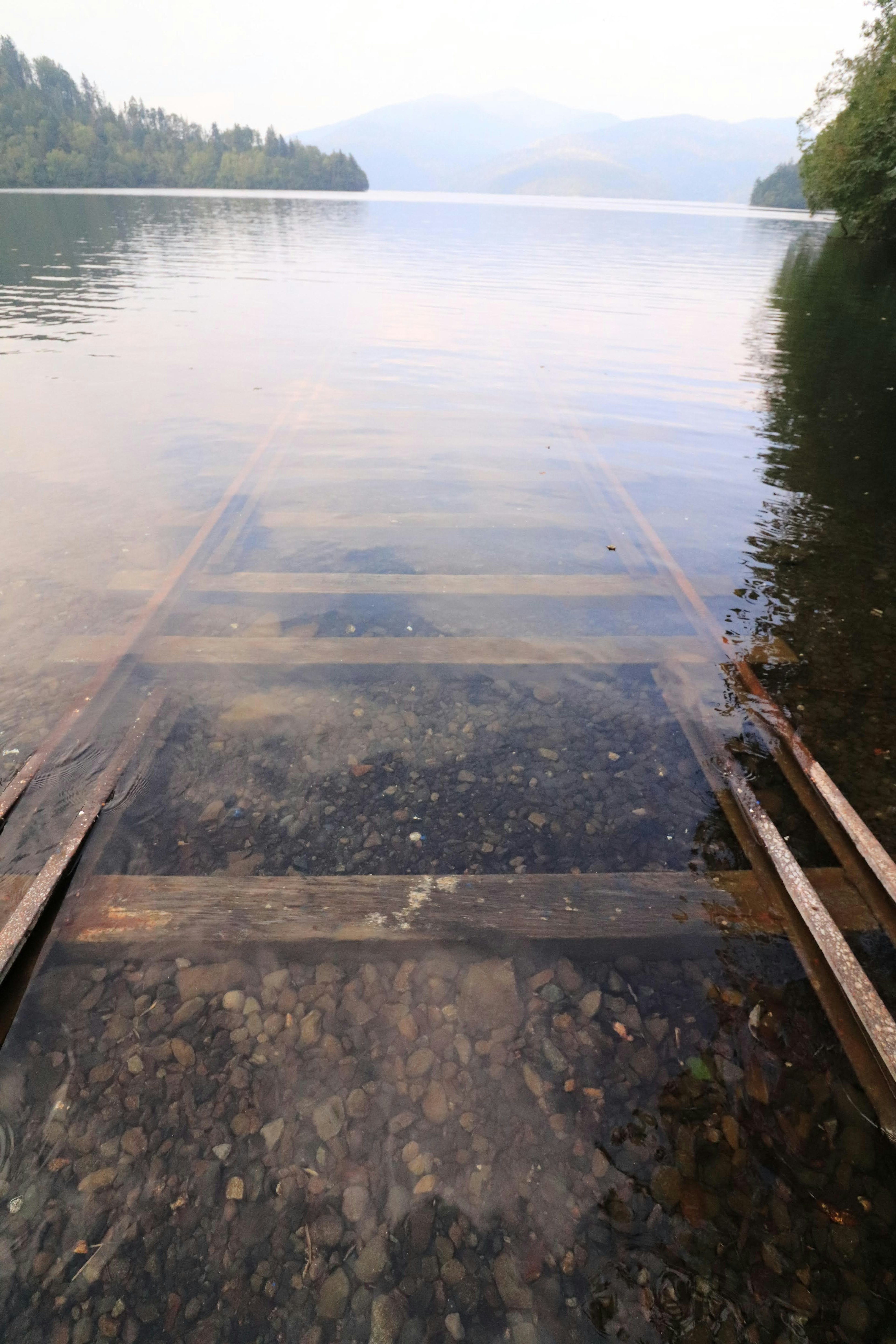 Bagian dari dermaga kayu yang terendam di air jernih danau