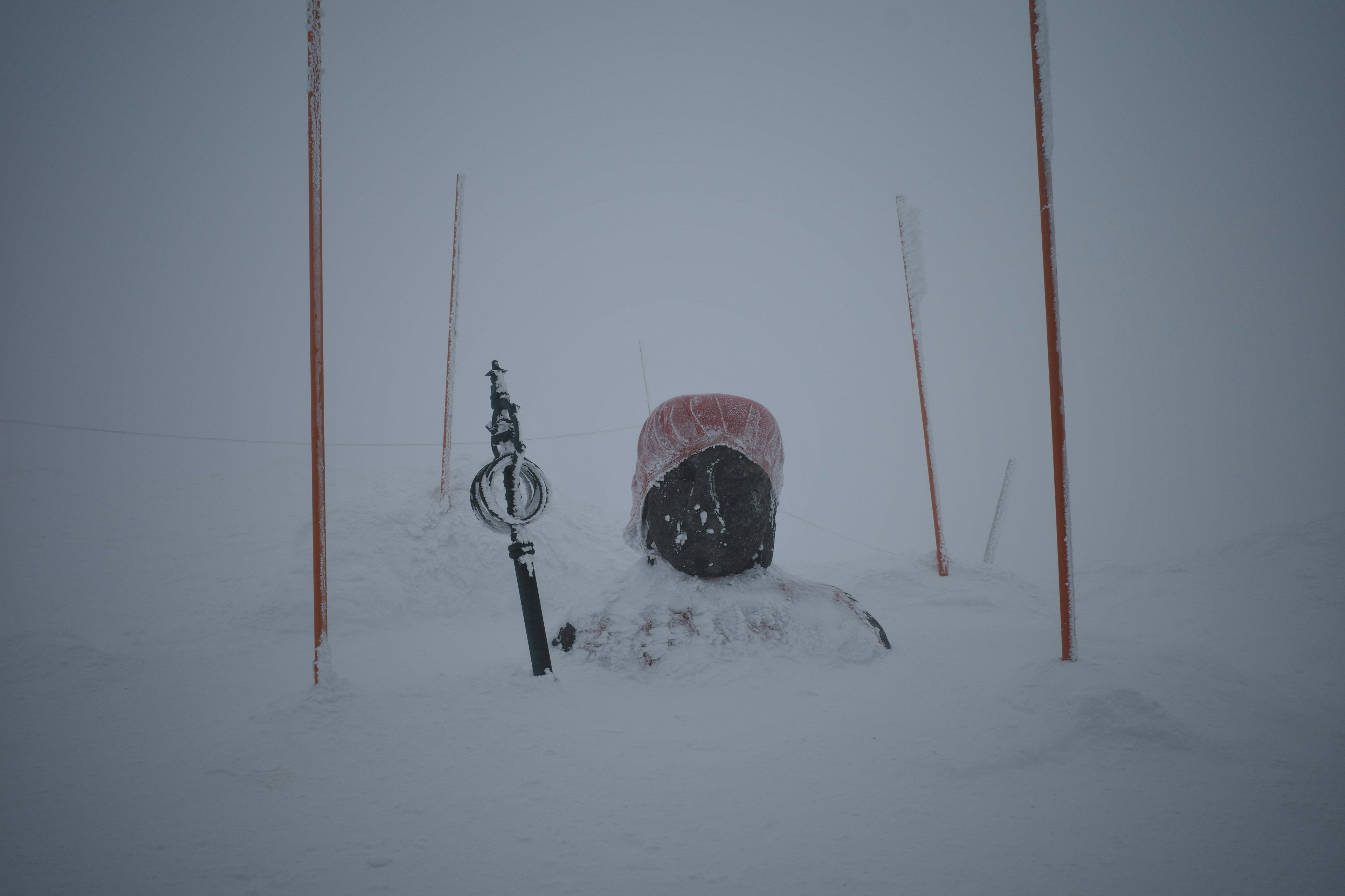 Snow-covered ski equipment with red poles in a winter landscape