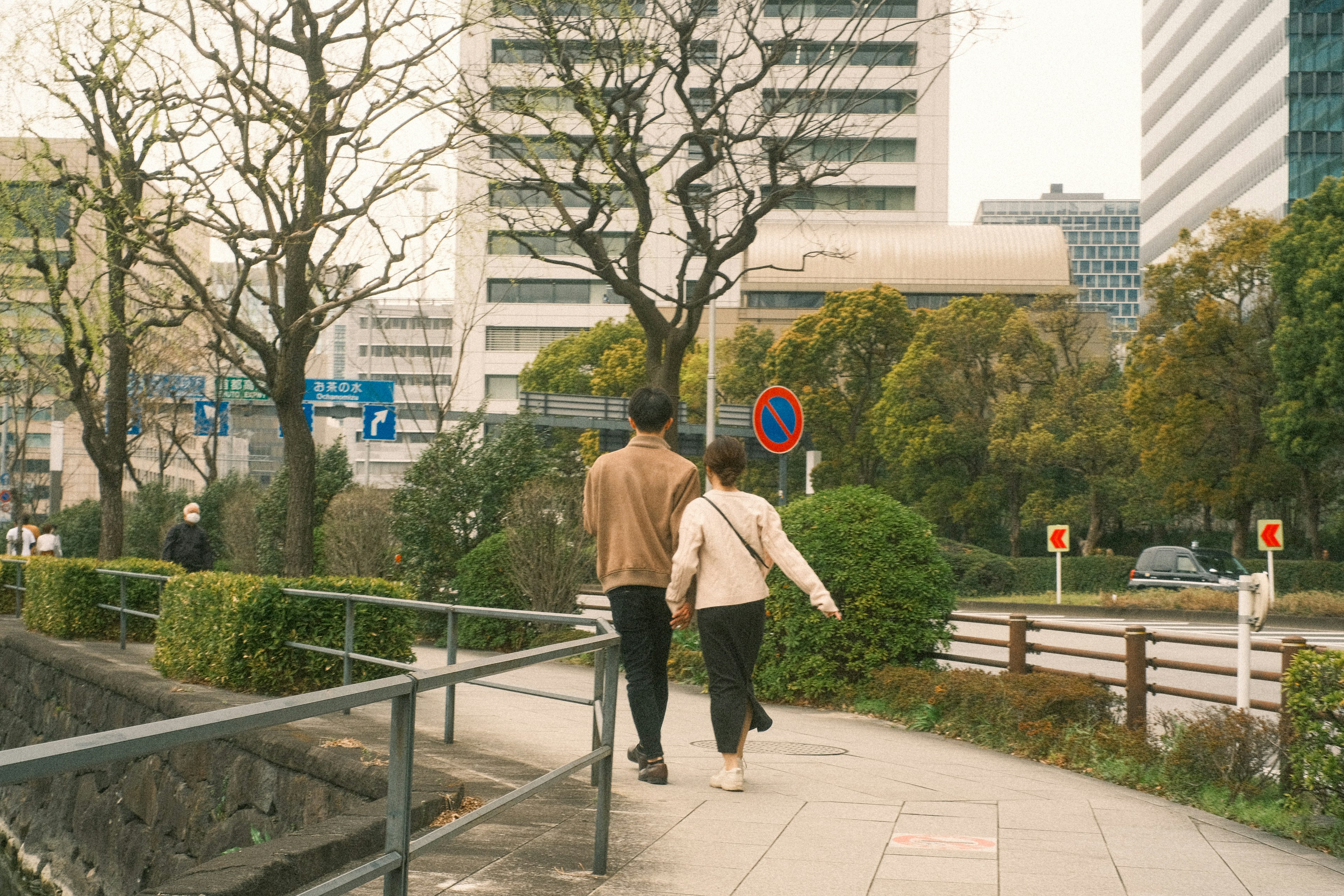 都市の歩道を歩くカップルと高層ビルの背景